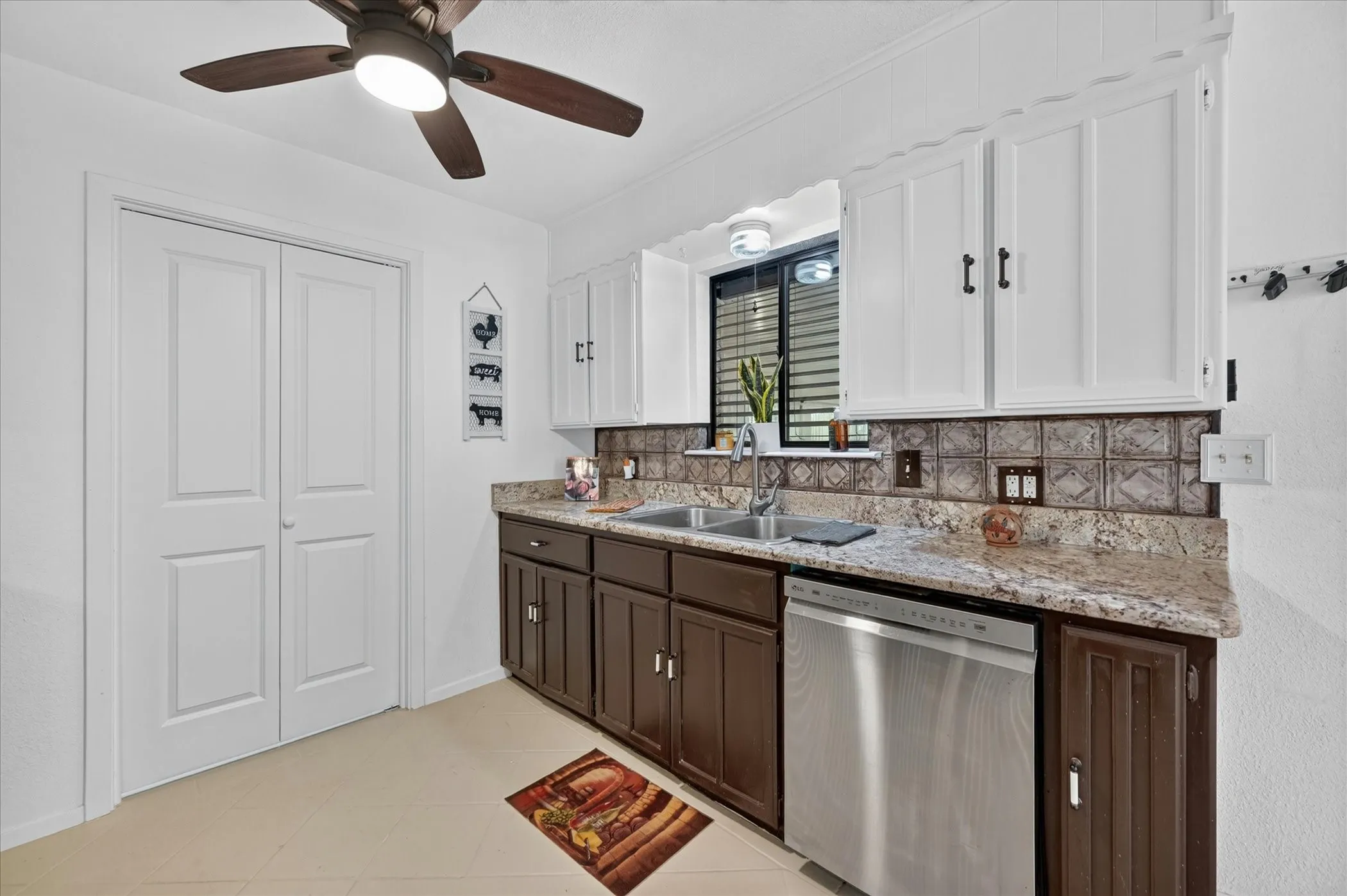 Kitchen featuring a dual-basin stainless steel sink, granite countertops, and a decorative tile backsplash