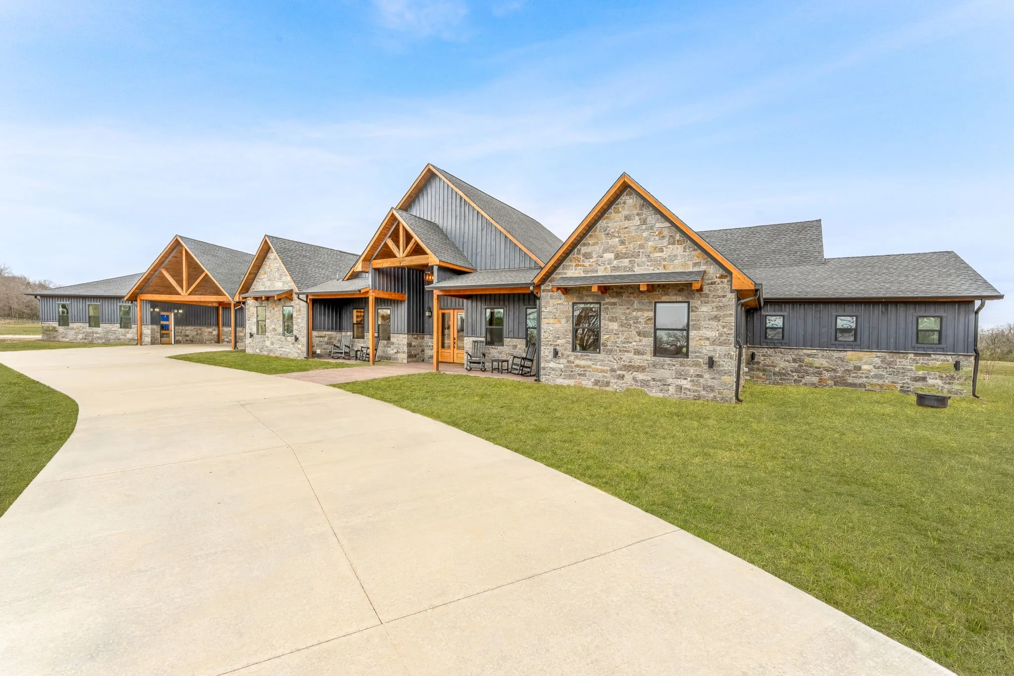 View of front facade featuring stone siding, a shingled roof, and board and batten siding