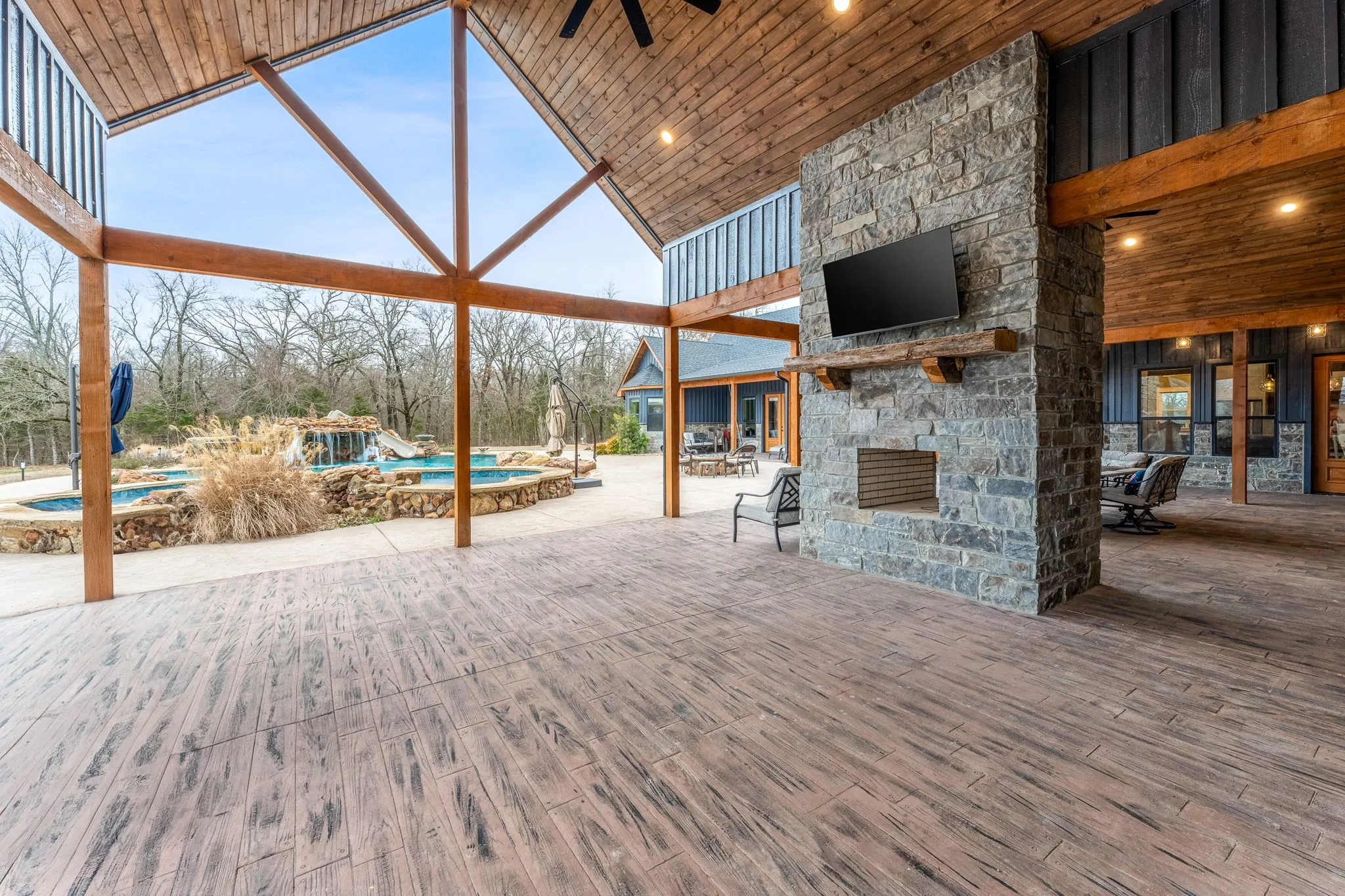 View of patio / terrace with an outdoor stone fireplace, an outdoor pool, ceiling fan, and outdoor dining area