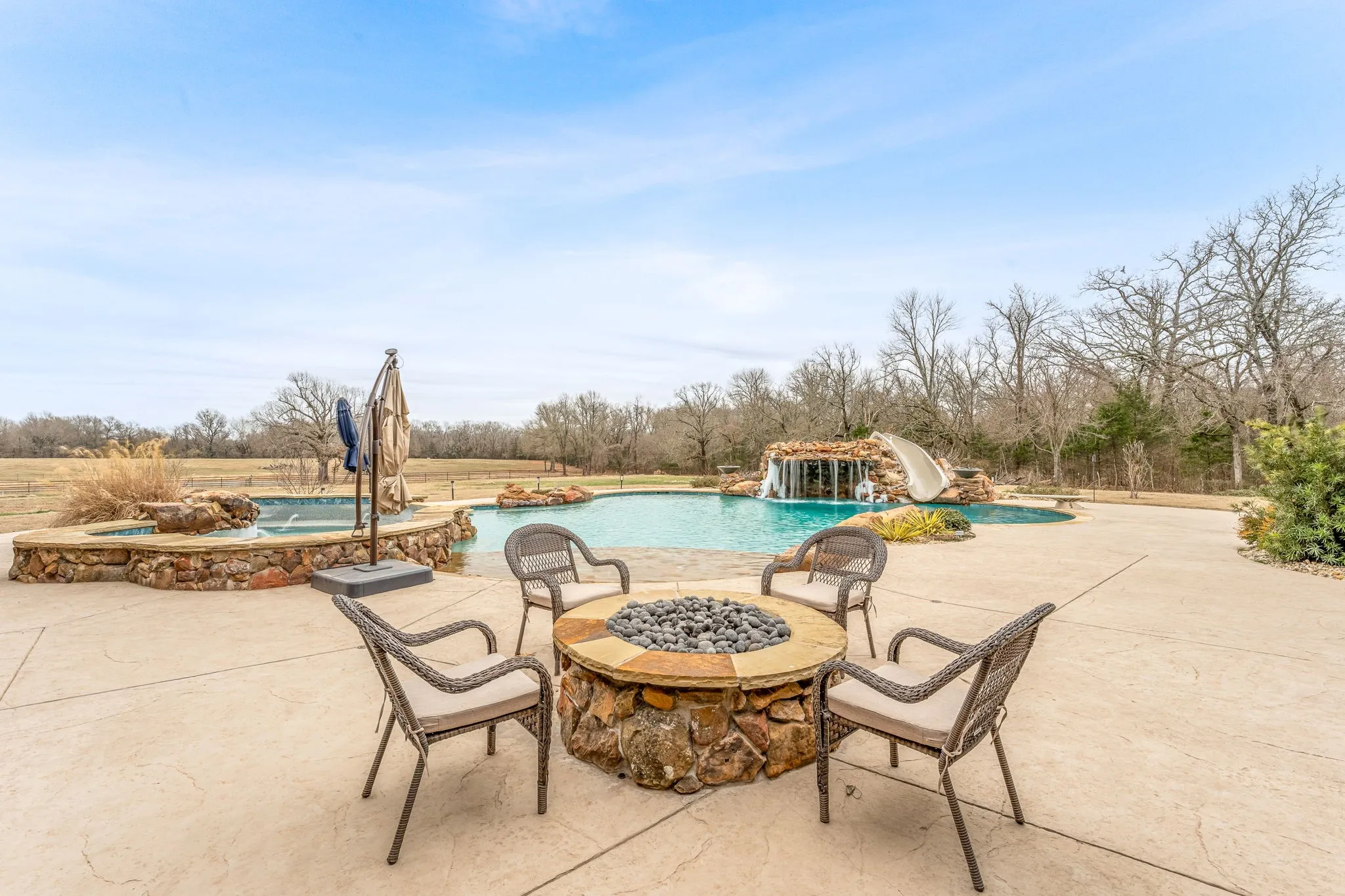 View of patio featuring a fire pit, an outdoor pool, and an in-ground hot tub