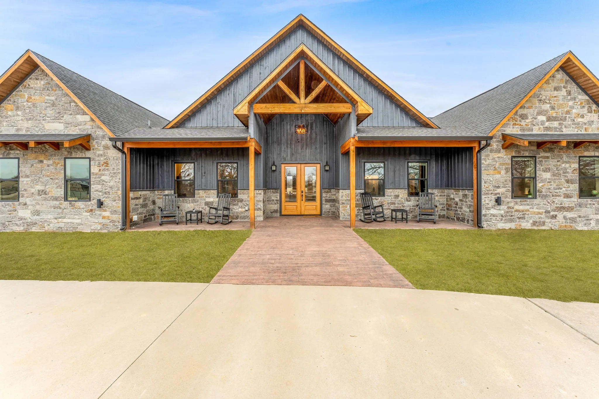 View of front of property with stone siding, a front yard, a porch, and french doors