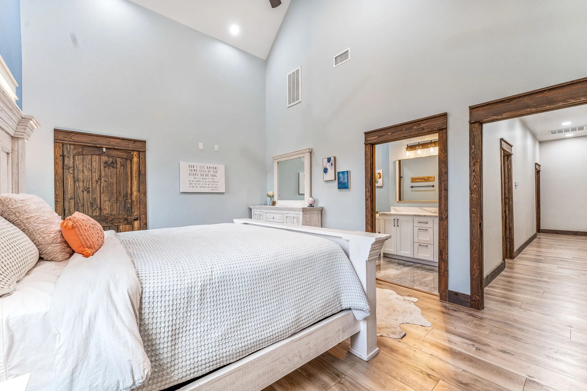 Bedroom with a high ceiling, light wood finished floors, ensuite bathroom, and recessed lighting