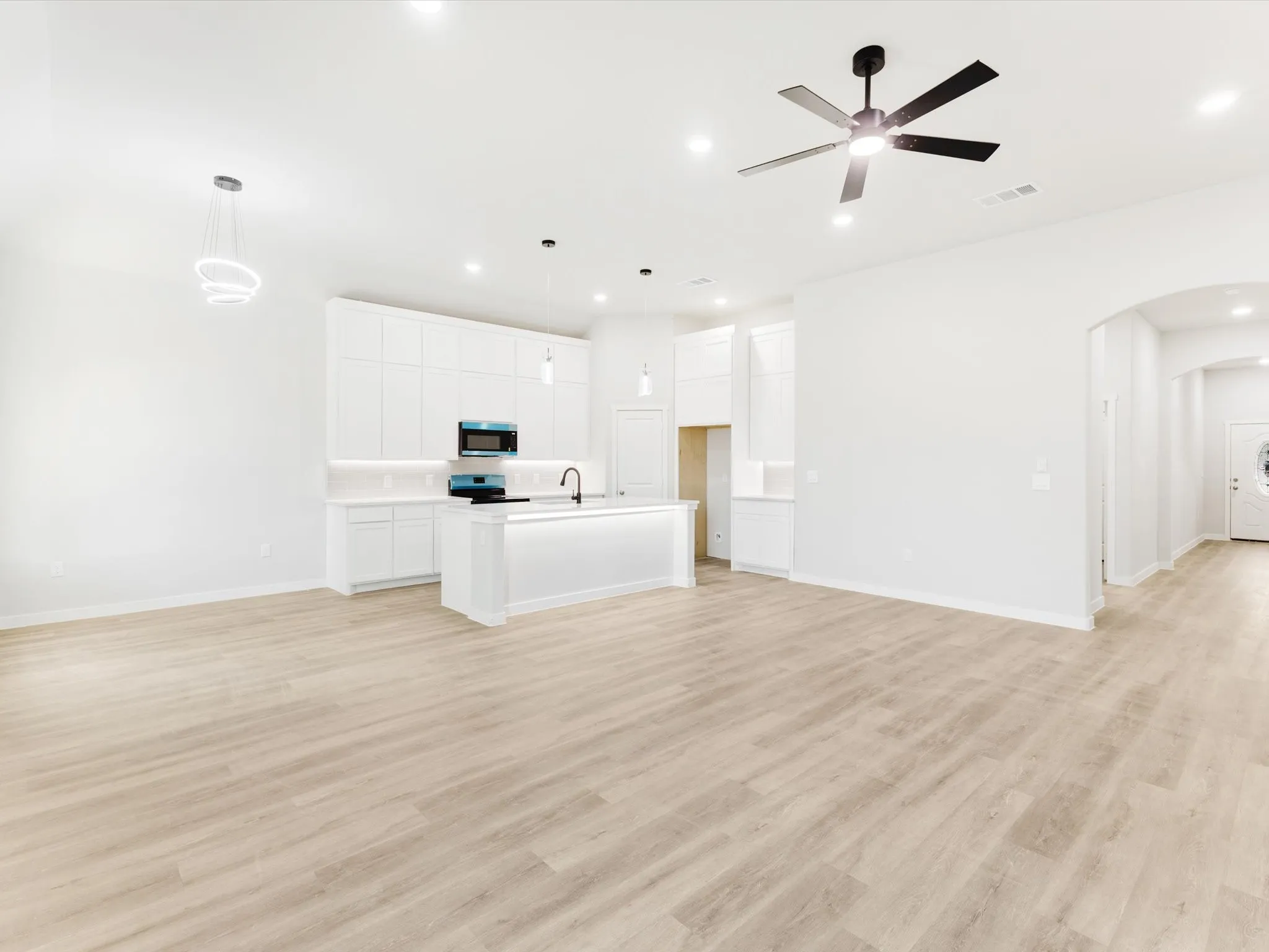 Open-concept living area featuring light wood-finish flooring, recessed lighting, and a modern ceiling fan