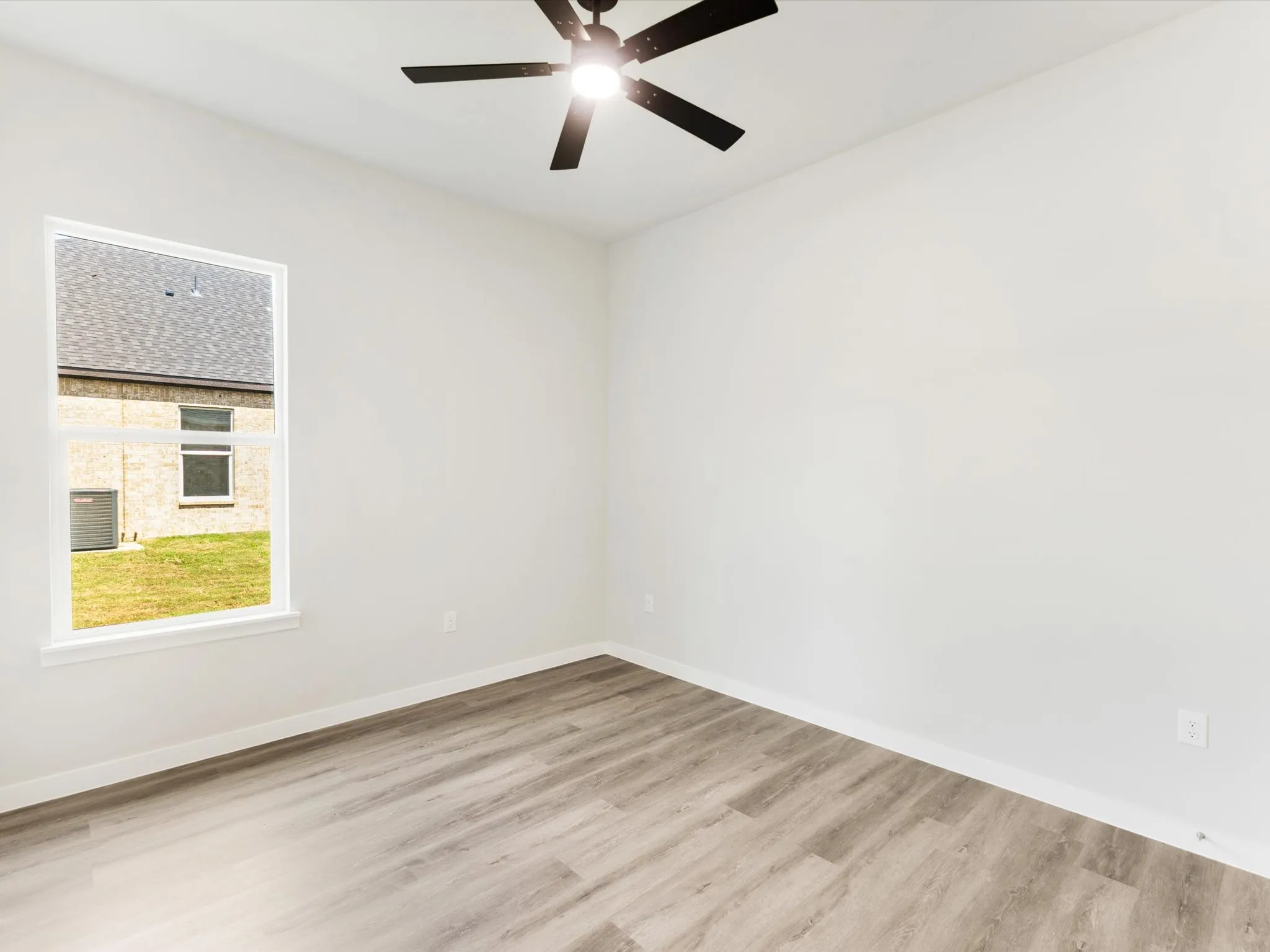 Bright interior with wood-finish flooring, a contemporary ceiling fan, and a single window