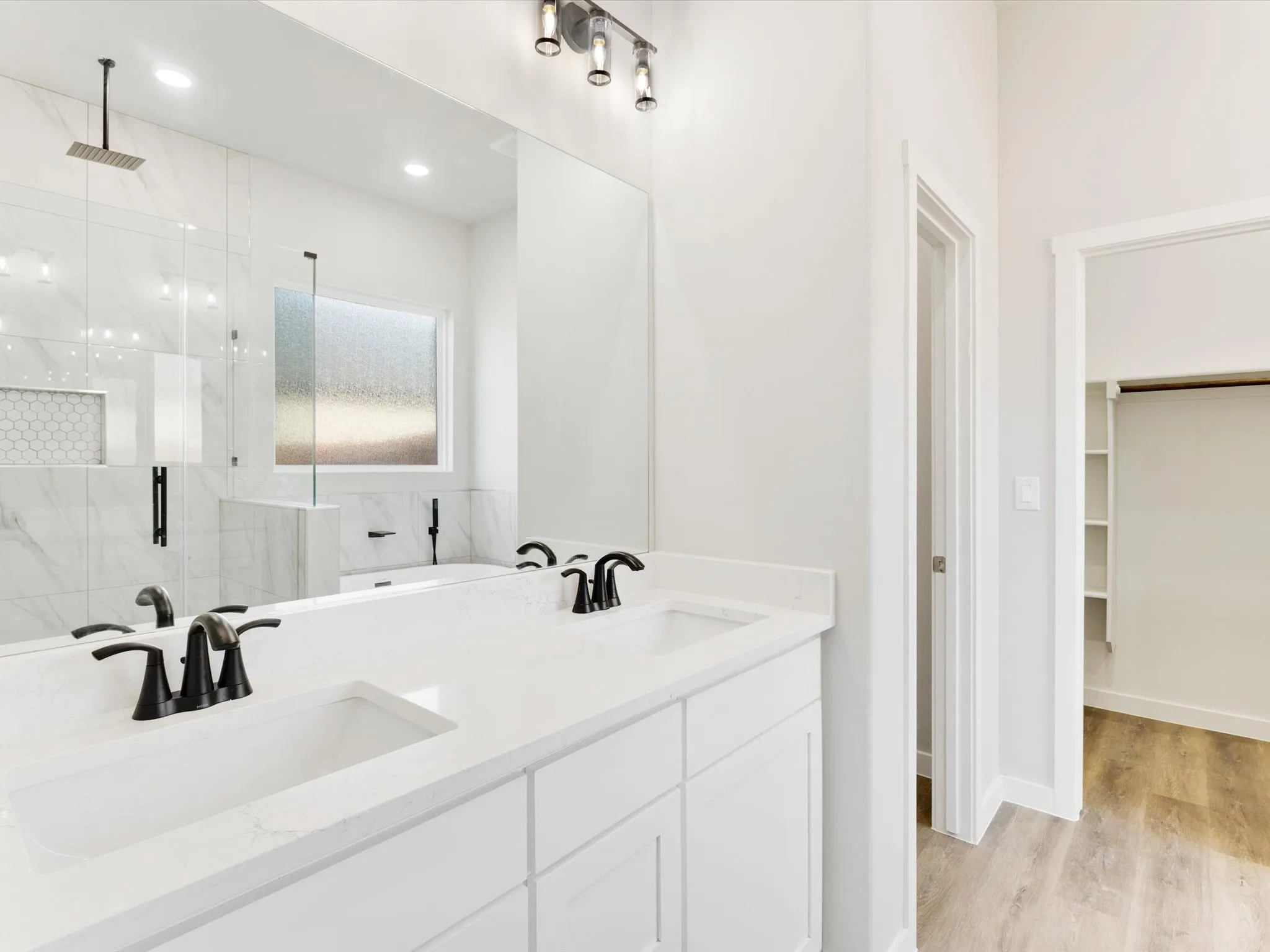 Double vanity with integrated sinks, white cabinetry, matte black fixtures, and a large wall mirror