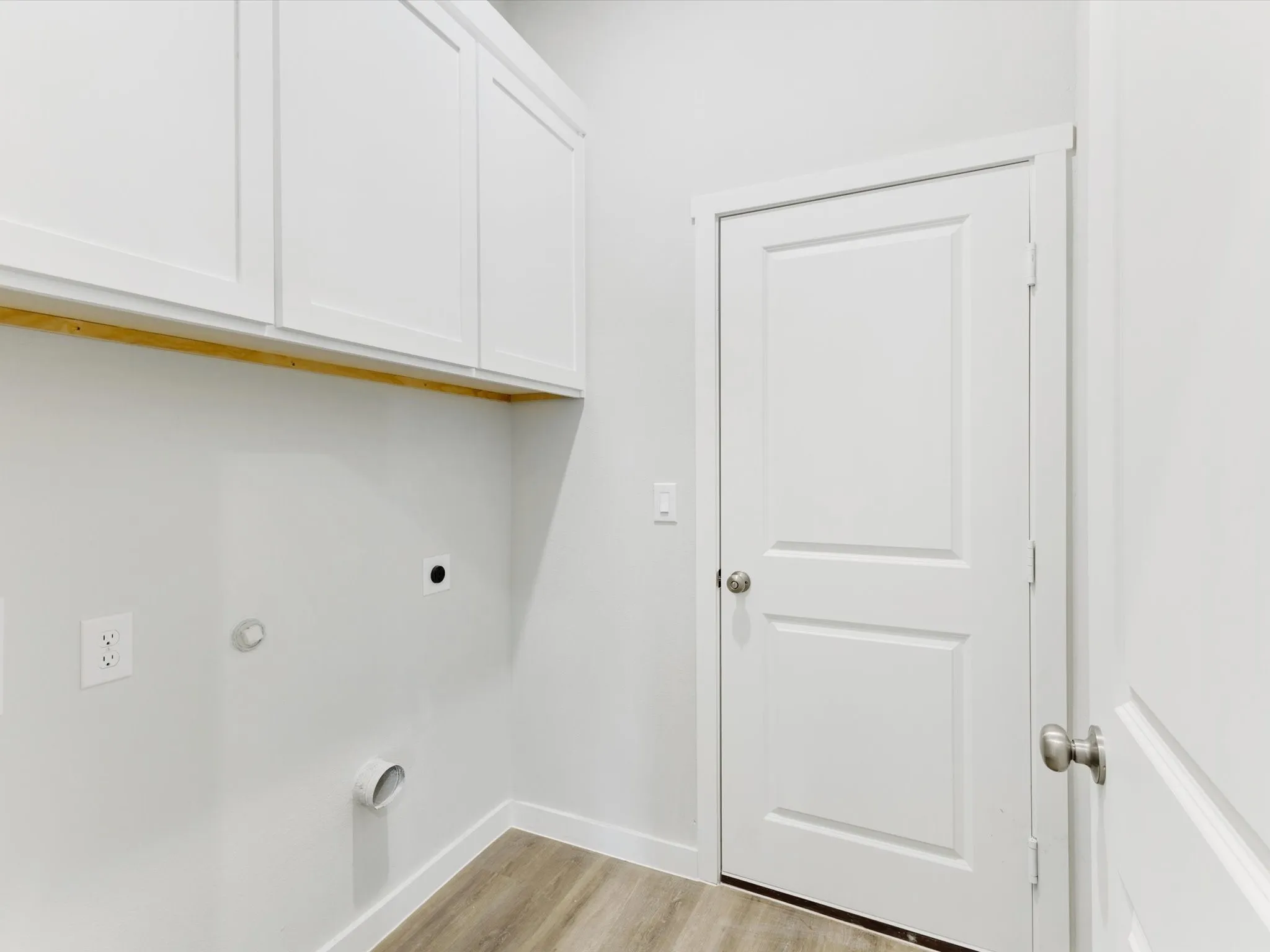 White shaker cabinetry, wood-finish flooring, and a paneled interior door