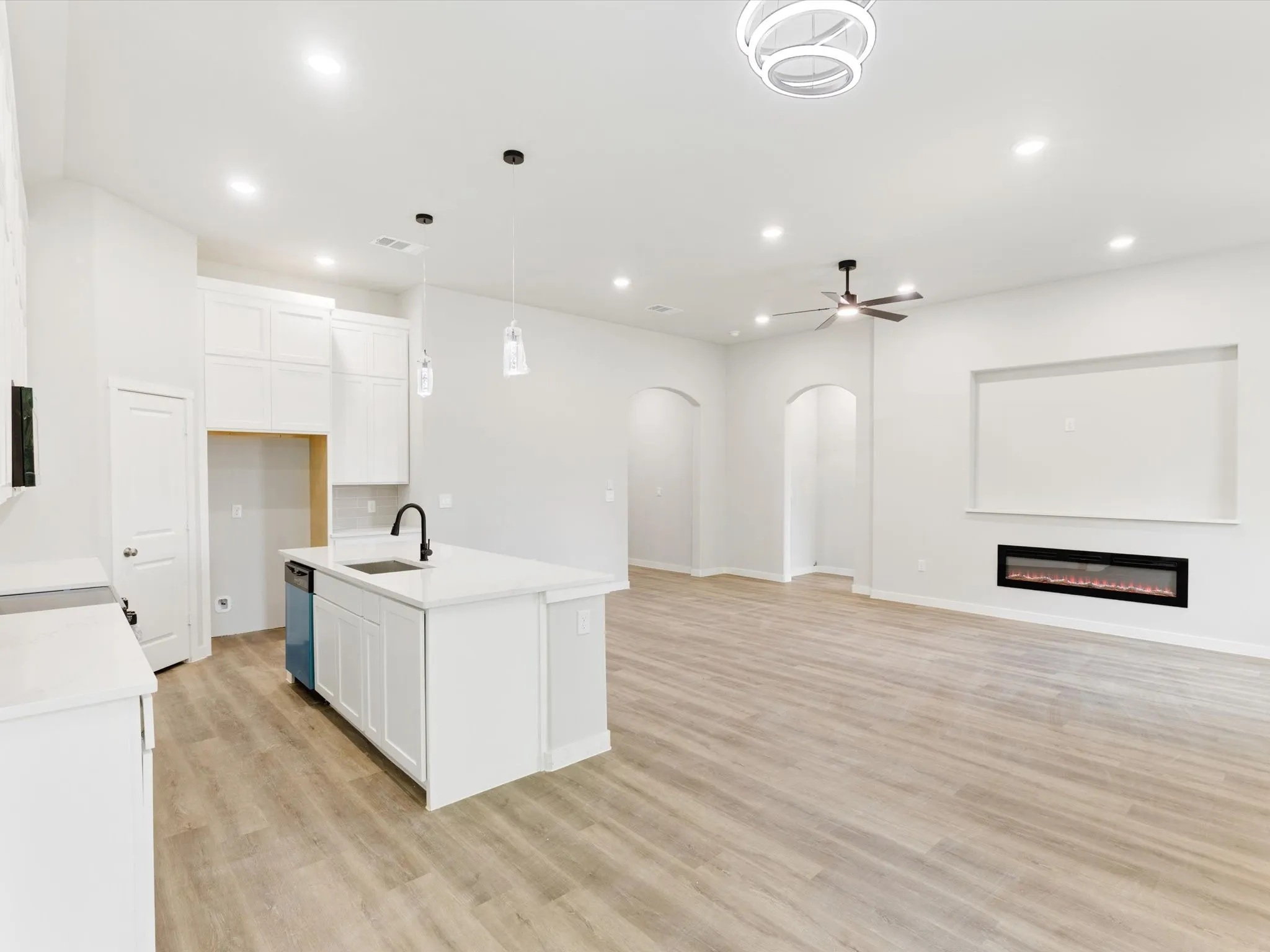 Open-concept living area featuring wood-finish flooring, recessed lighting, and a linear electric fireplace