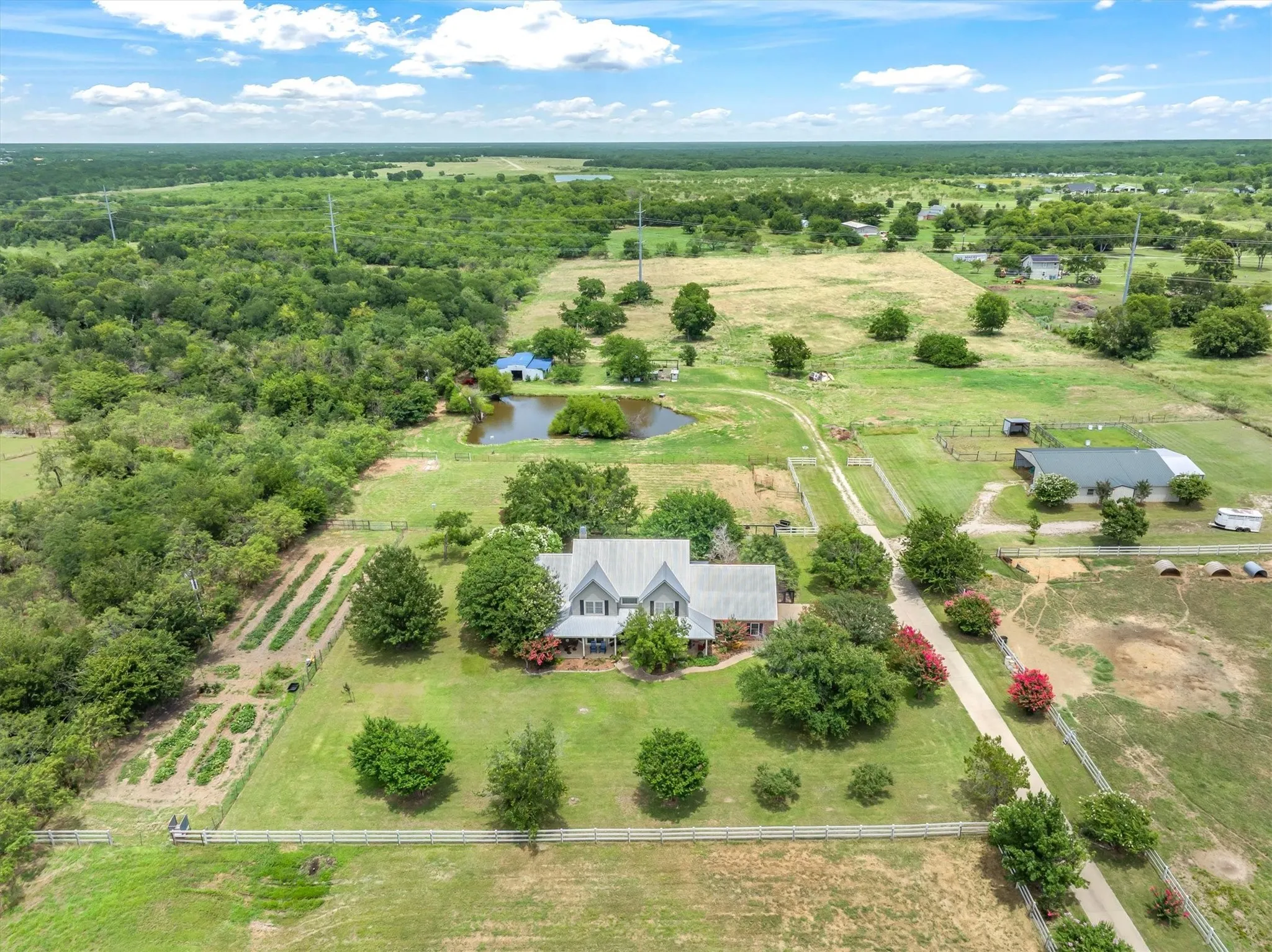 Home in foreground, horse barn with apartment to right, and equipment or hay barn in back.