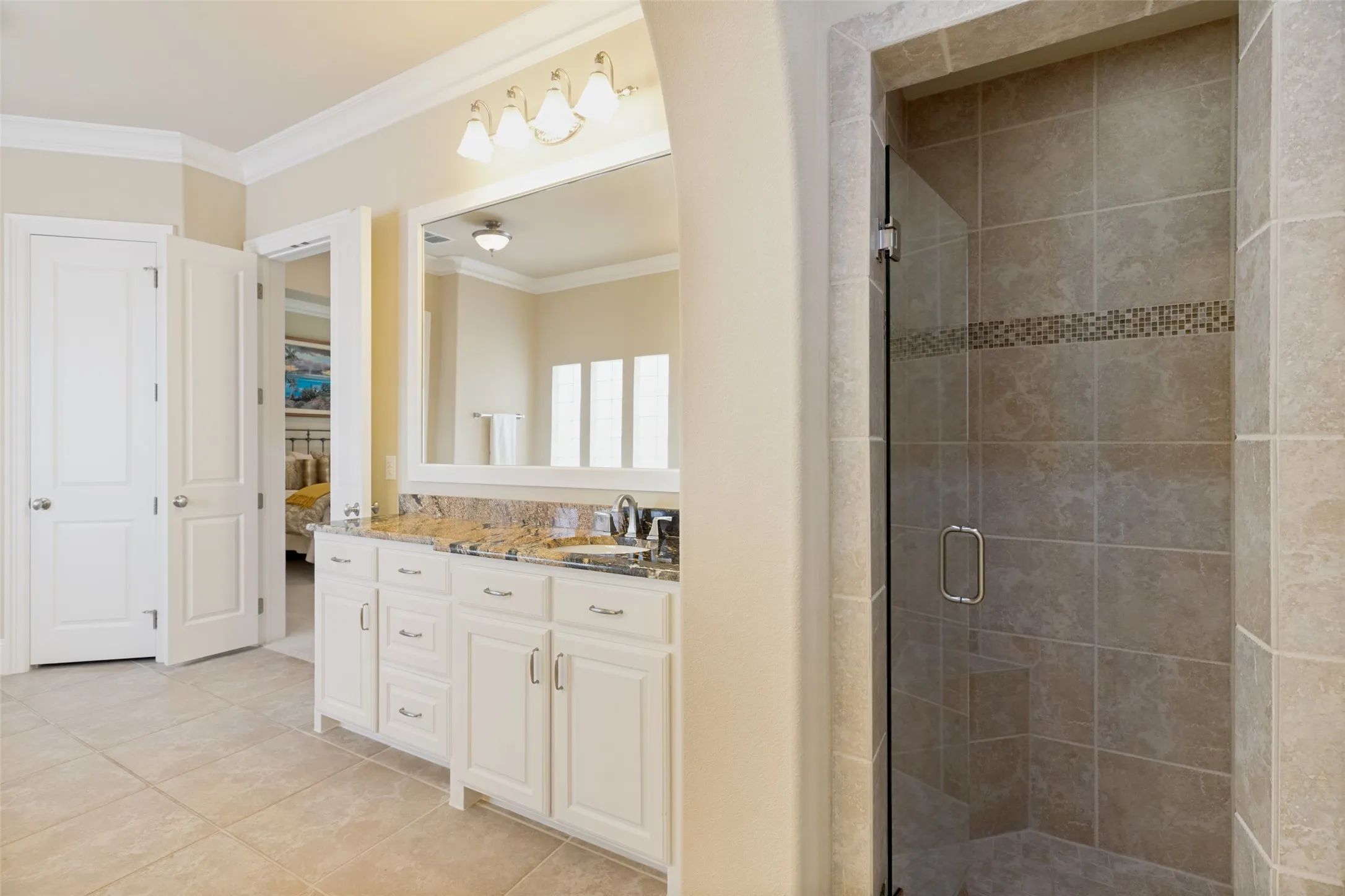 Whether you prefer a soaking bubble bath or a brisk shower, this bathroom provides both.  The roomy shower has a floor tile surround with a decorative band of small square tiles.  Owners will love the two roomy closets - one with direct access to the laundry room, and there is also a linen closet.  Crown molding at the ceiling and ceramic tile on the floor finish this pretty spa-influenced bath.