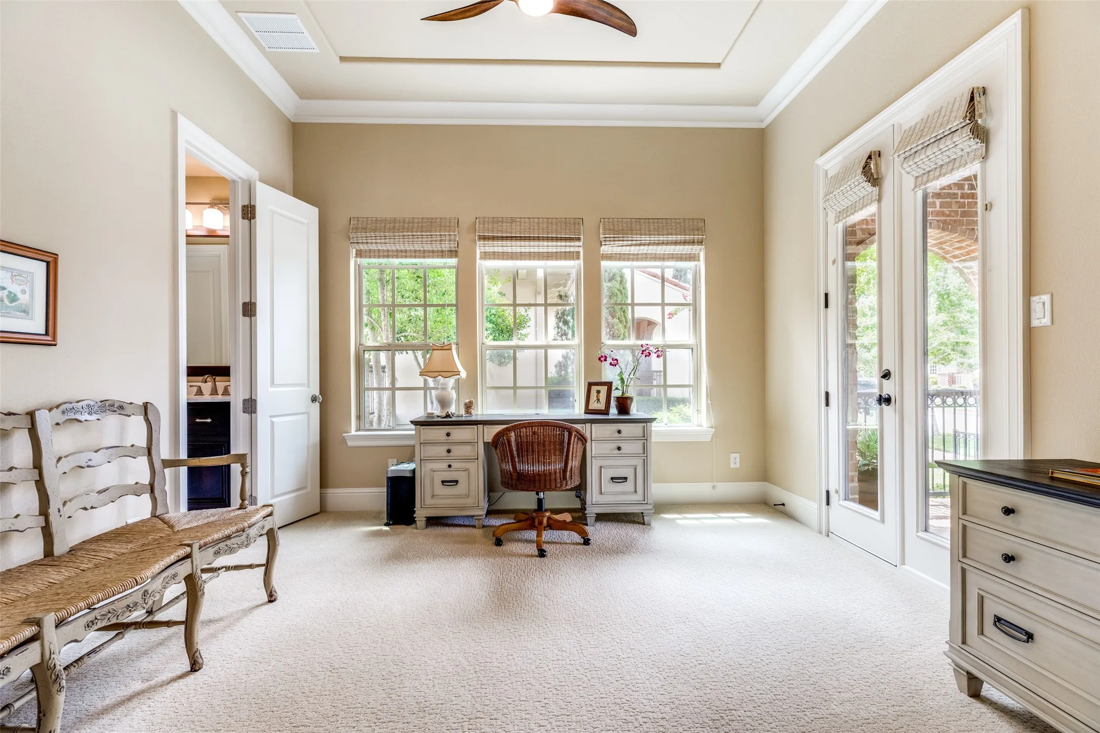 This attractive room has flexible uses.  With an adjoining full bath and closet, the room could be a 4th bedroom if needed or it makes a very comfortable space to work at home.  Three windows with shades view the side of the home and allow abundant light.  Shades cover the windows.  Soft carpet is on the floor and a breezy ceiling fan is above in the raised ceiling.