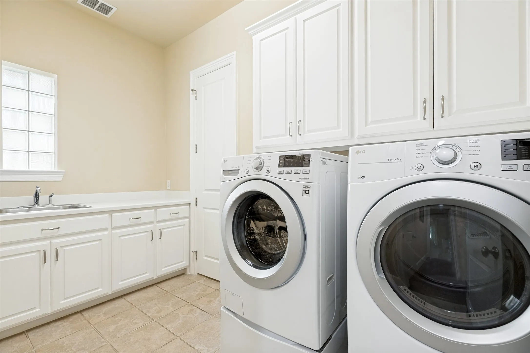 This large laundry room is on every buyer's wish list.  Plenty of room for a washer and dryer is topped with built-in cabinets.  A wide countertop with a window above has a handy stainless sink and space for storage and folding.  And, there is direct access to one of the primary closets.  The ceramic tile floor is ideal for a useful laundry room.
