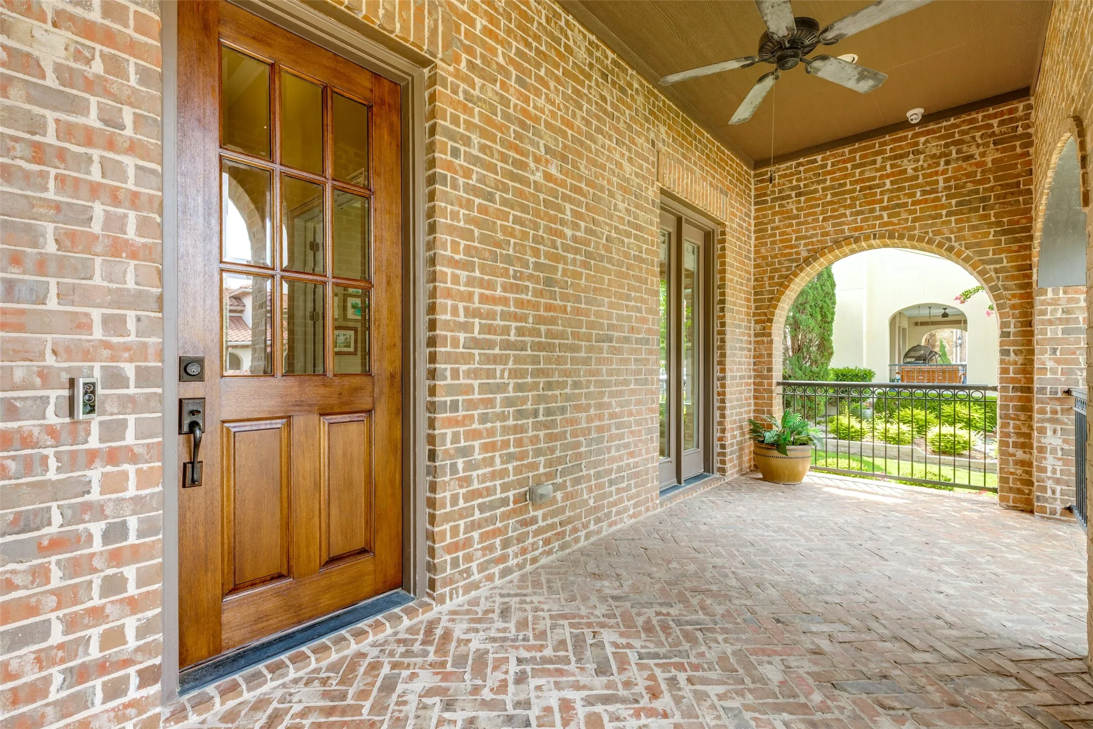 This inviting front porch is the perfect spot for a cup of coffee or beverage while you visit with neighbors and enjoy the outdoors.  Bricks with an intricate herringbone design line the porch floor, and wide arches with iron railing add character.  A pair of doors provide access to the porch from the home office.  A ceiling fan and recessed lights add to the enjoyment.