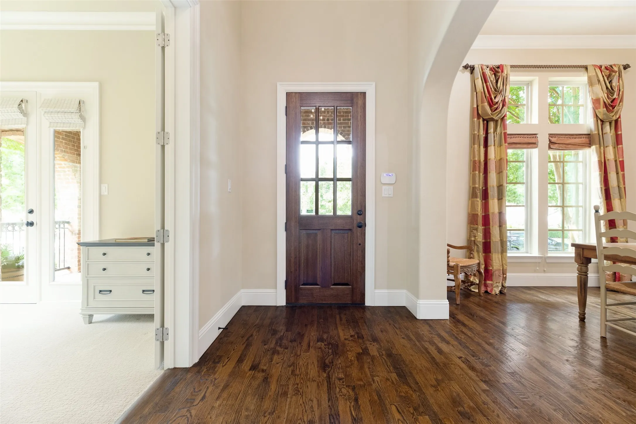 Upon entering through the eight-foot wood door with glass panels, guests are greeted by a tall foyer with a raised ceiling, crown molding and tall baseboards.  An iron chandelier is at the ceiling.  Solid 3/4 inch wood floors begin at the entry and flow though living and dining areas.  A wide arch opens to the formal dining room on one side.