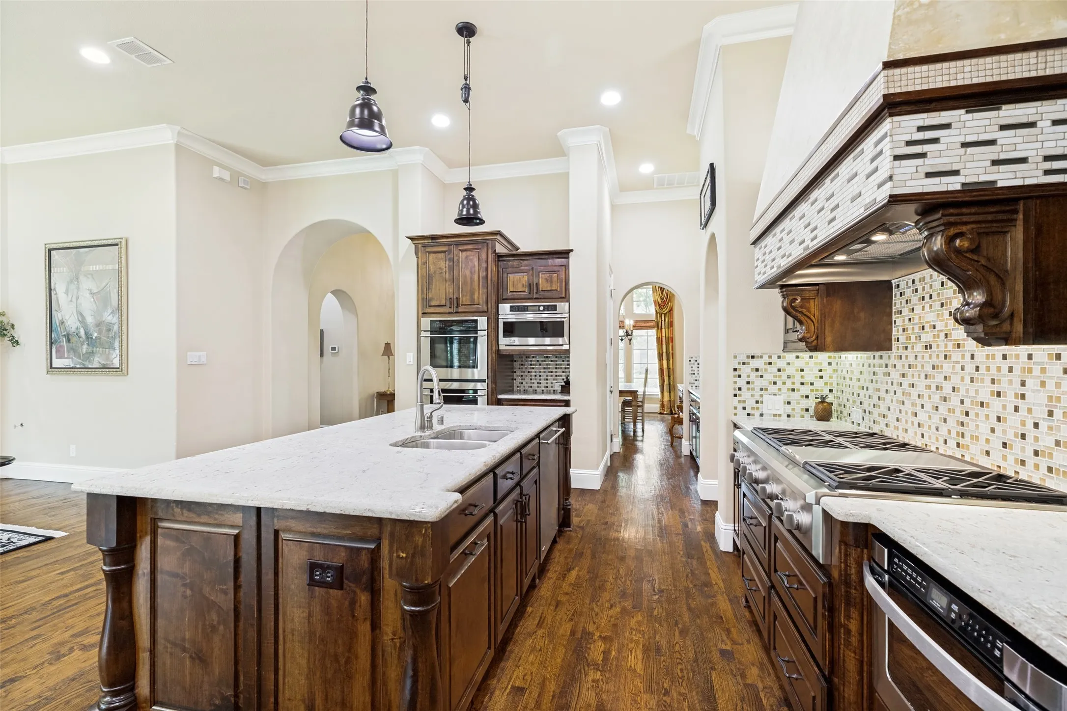 Attractive small square metallic tiles form a backsplash above the countertops and coordinating tile decorates the vent hood.  Decorative corbels pull out for spice storage.  The island holds a stainless double sink, the stainless dishwasher and a trash drawer.
