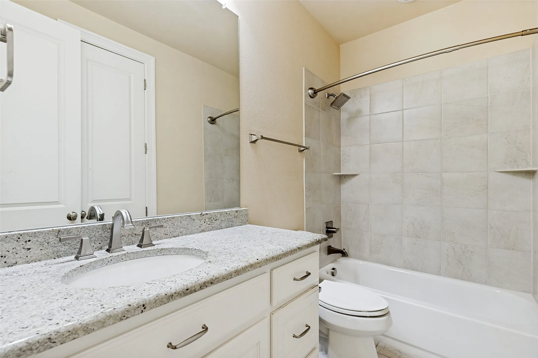 The en-suite bath for the guest room, has white cabinets with granite countertops and an undermount sink.  A wide mirror with lights above and brushed nickel hardware and faucet are available.  The tub/shower has floor tile as a surround and ceramic tile is on the floor.  There is also a walk-in closet.