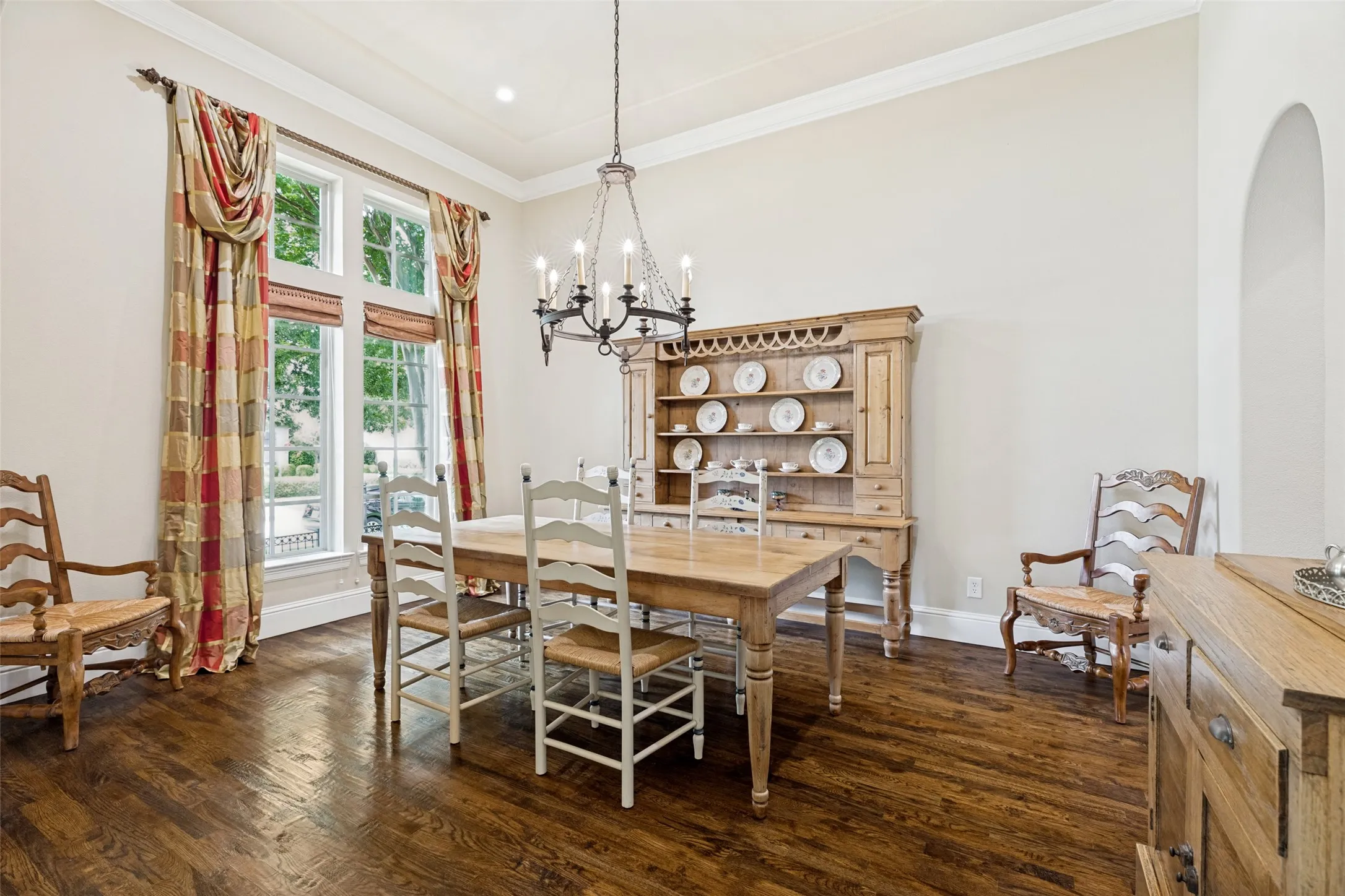 Special family occasions and entertaining will be enjoyable in the elegant formal dining room.  The wood floors, crown molding and tall baseboards continue into the room.  A chandelier matching the one in the entry as well as recessed lights illuminate the room, and a pair of windows topped by transom windows allow natural light and a nice view of the front.  Custom draperies decorate the windows and shades are available for privacy if desired. The arched casement leads to the butler's pantry and the kitchen beyond - very handy for food service.
