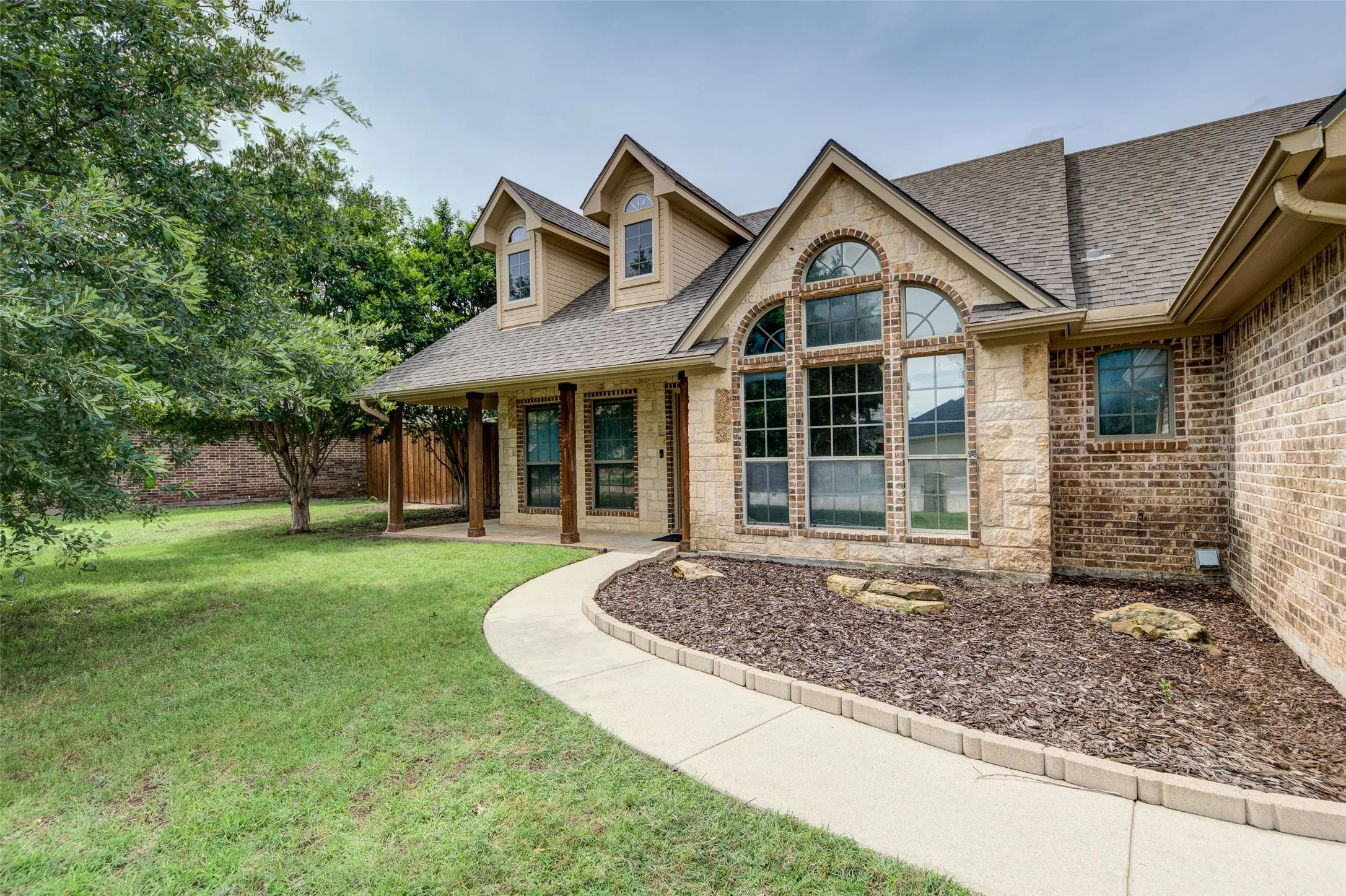 Attractive brick and stone exterior with mature landscaping and driveway.