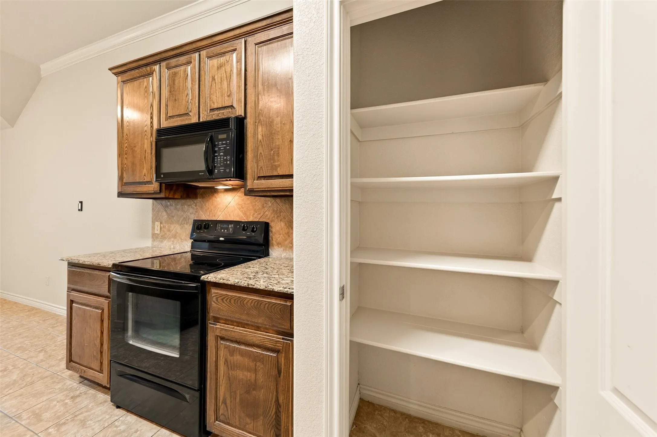 Kitchen area featuring wood cabinetry, granite-style countertops, and a tile backsplash