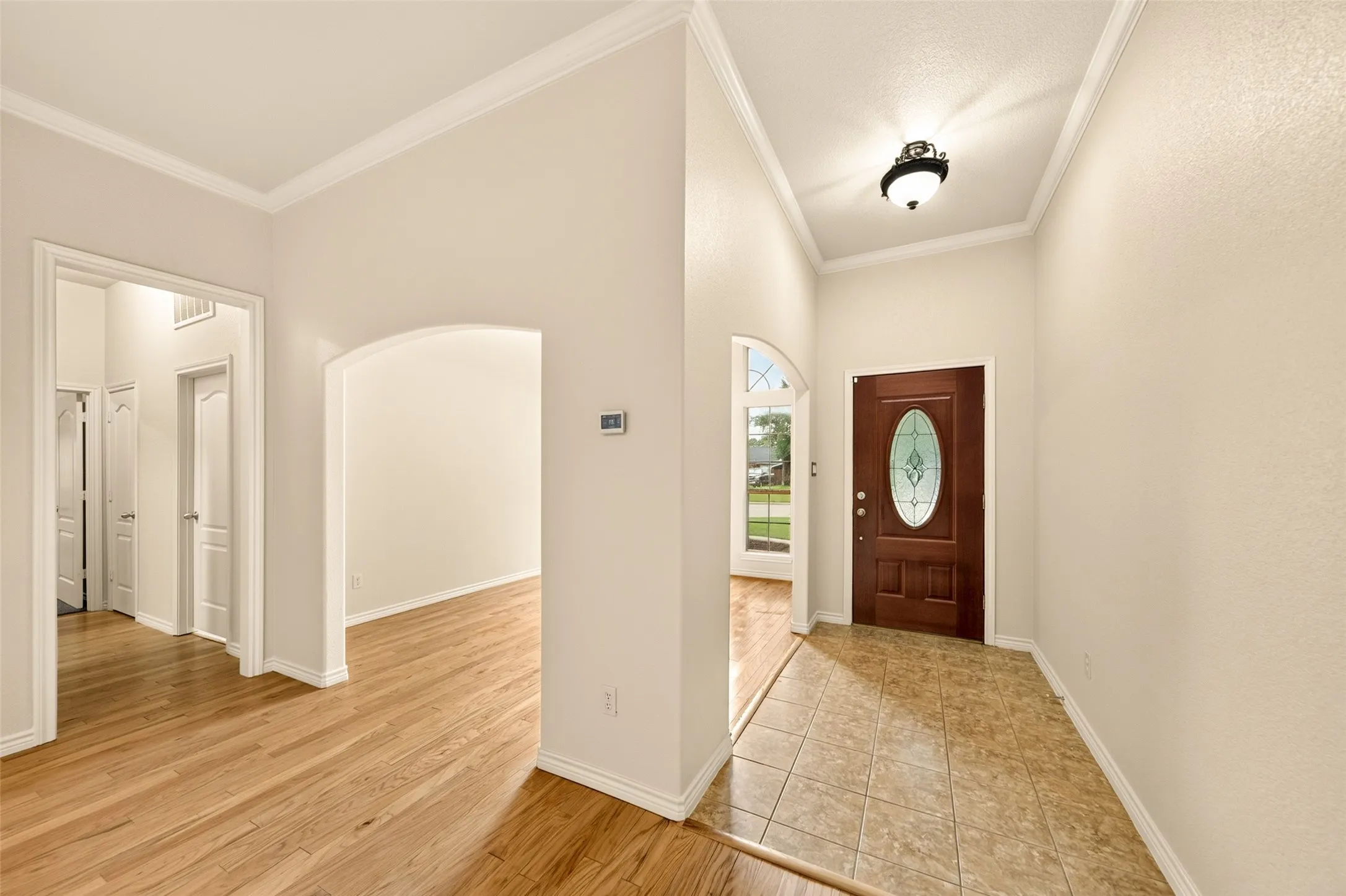 Entryway featuring a decorative dark wood-paneled door with an oval-shaped stained glass window, complemented by a ceiling-mounted light fixture