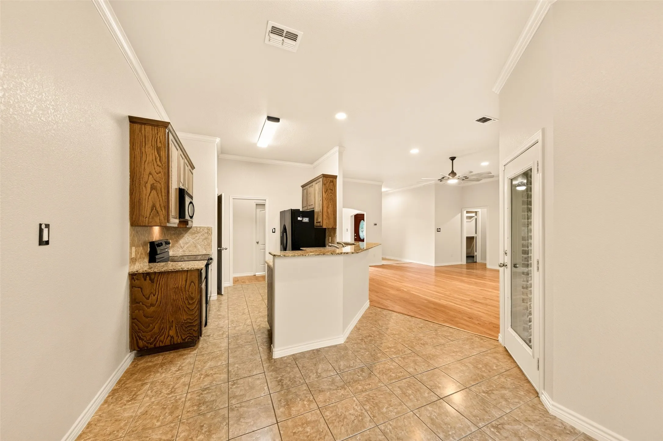Kitchen featuring wood cabinetry, integrated microwave, and granite-style countertops with tile backsplash