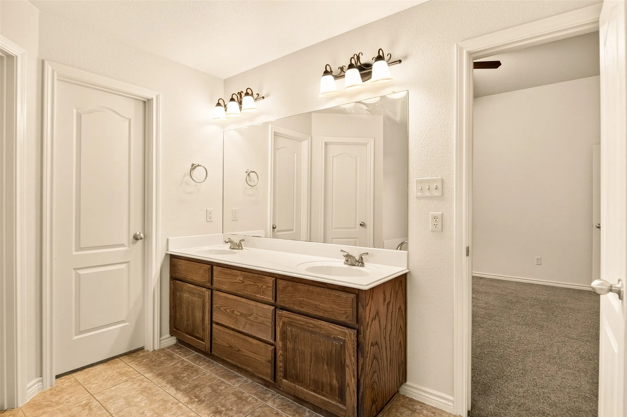 Double vanity with wood-finish cabinetry, white countertop, and dual sinks