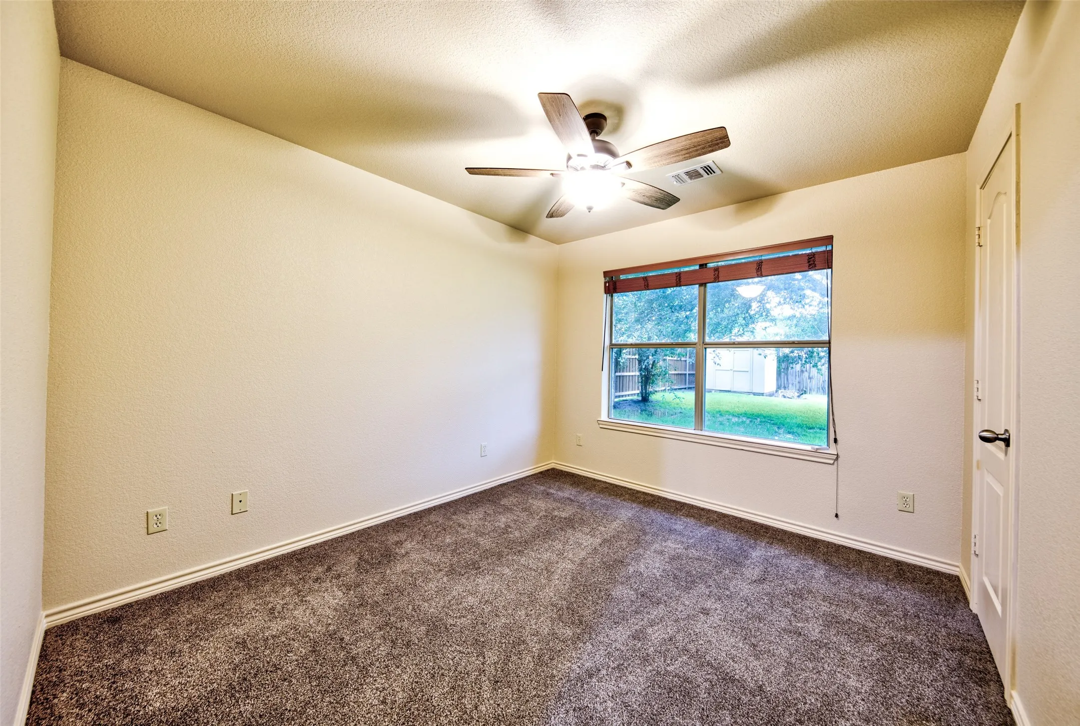 Spacious room featuring textured walls and soft grae carpeting