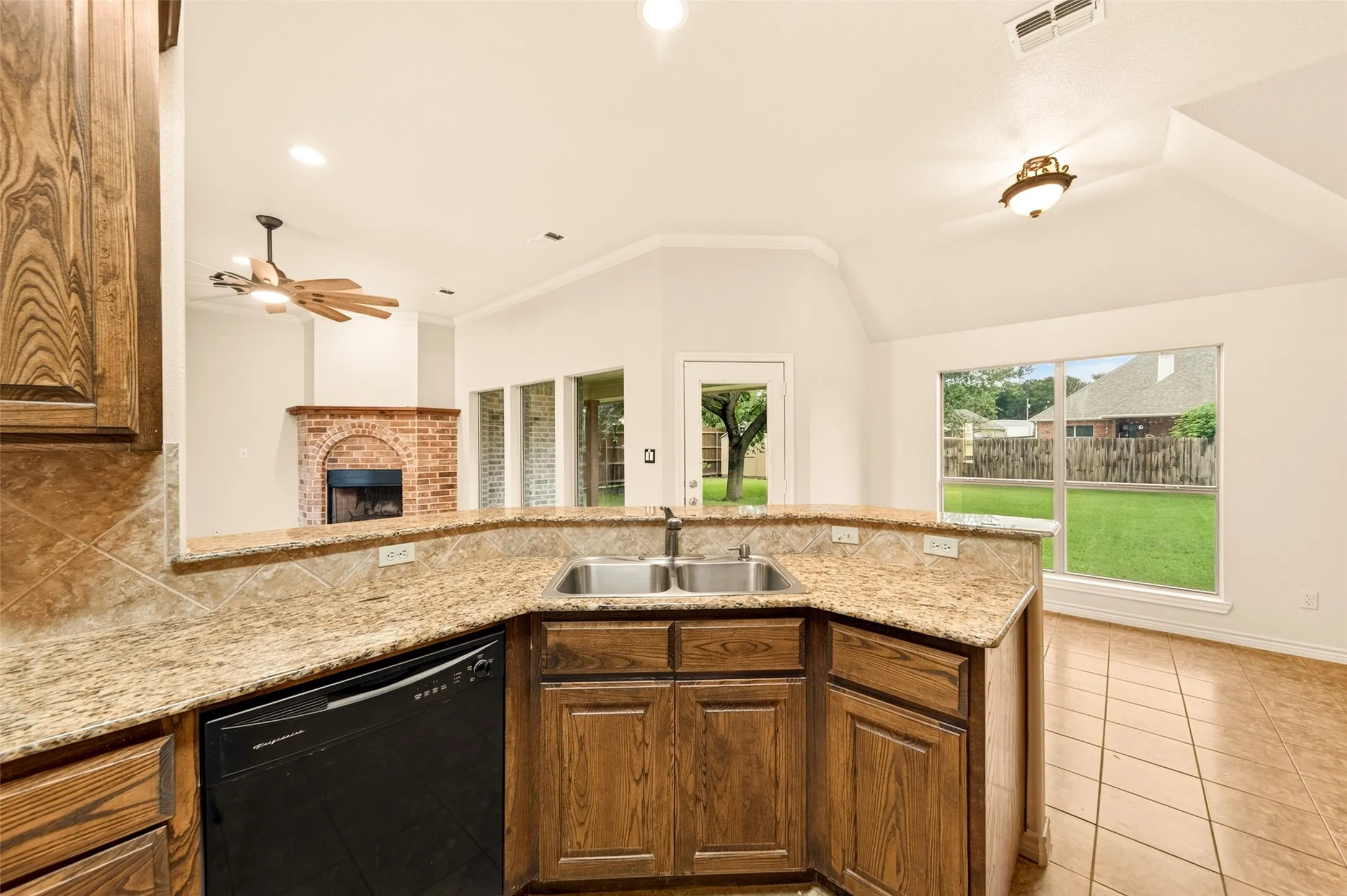 Kitchen featuring a double basin sink, granite-style countertops, and wood-finish cabinetry
