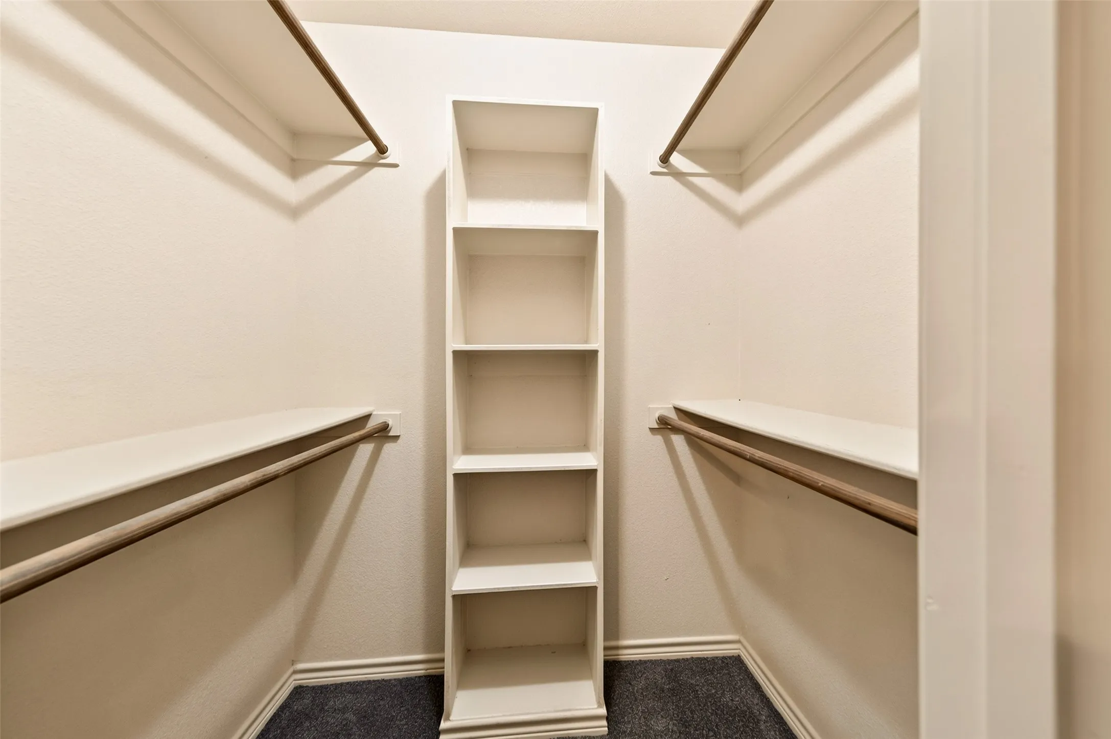 Built-in closet system featuring shelving, hanging rods, and dark carpeting