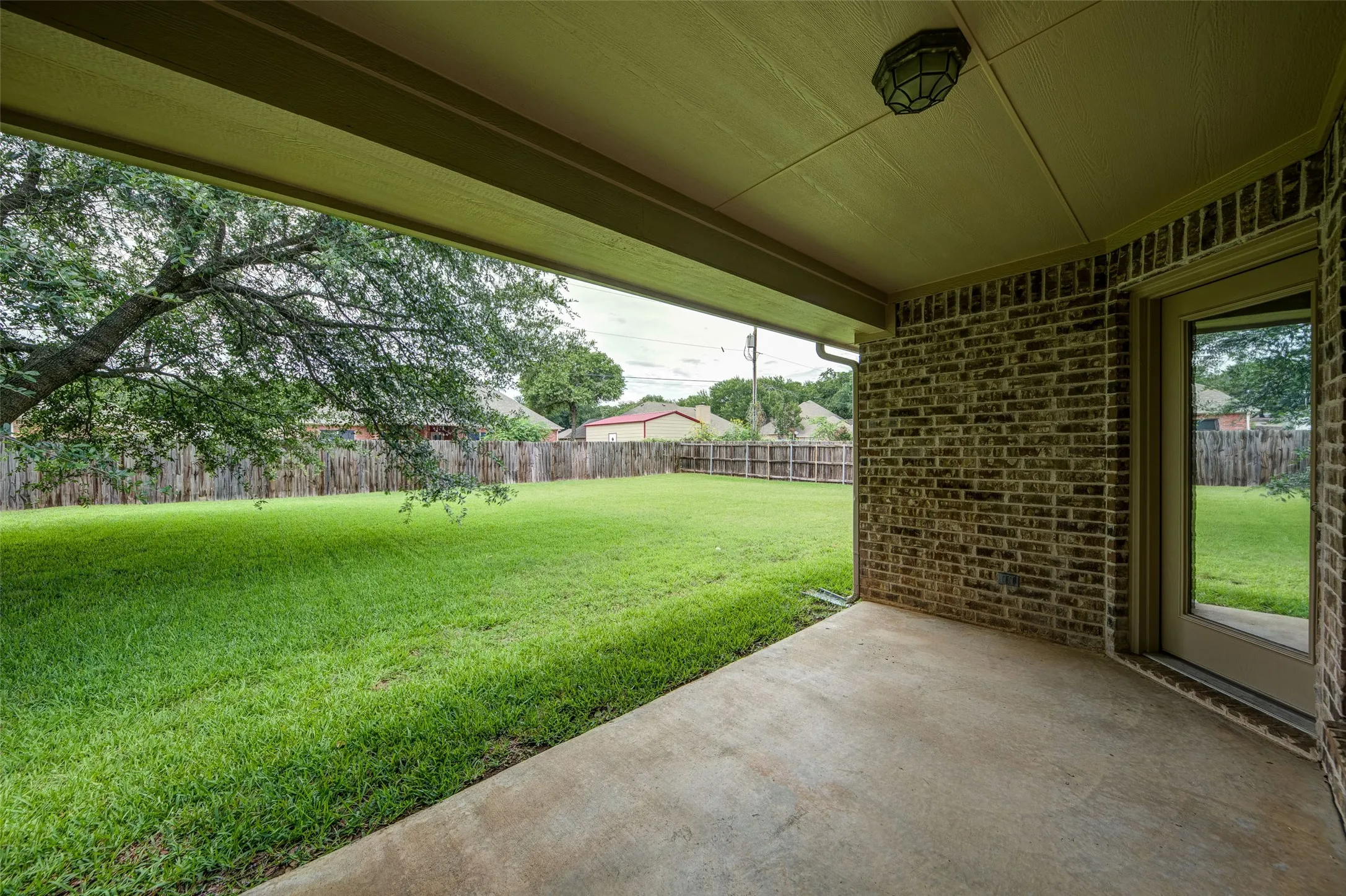 Covered back patio overlooking a spacious, fully fenced backyard.