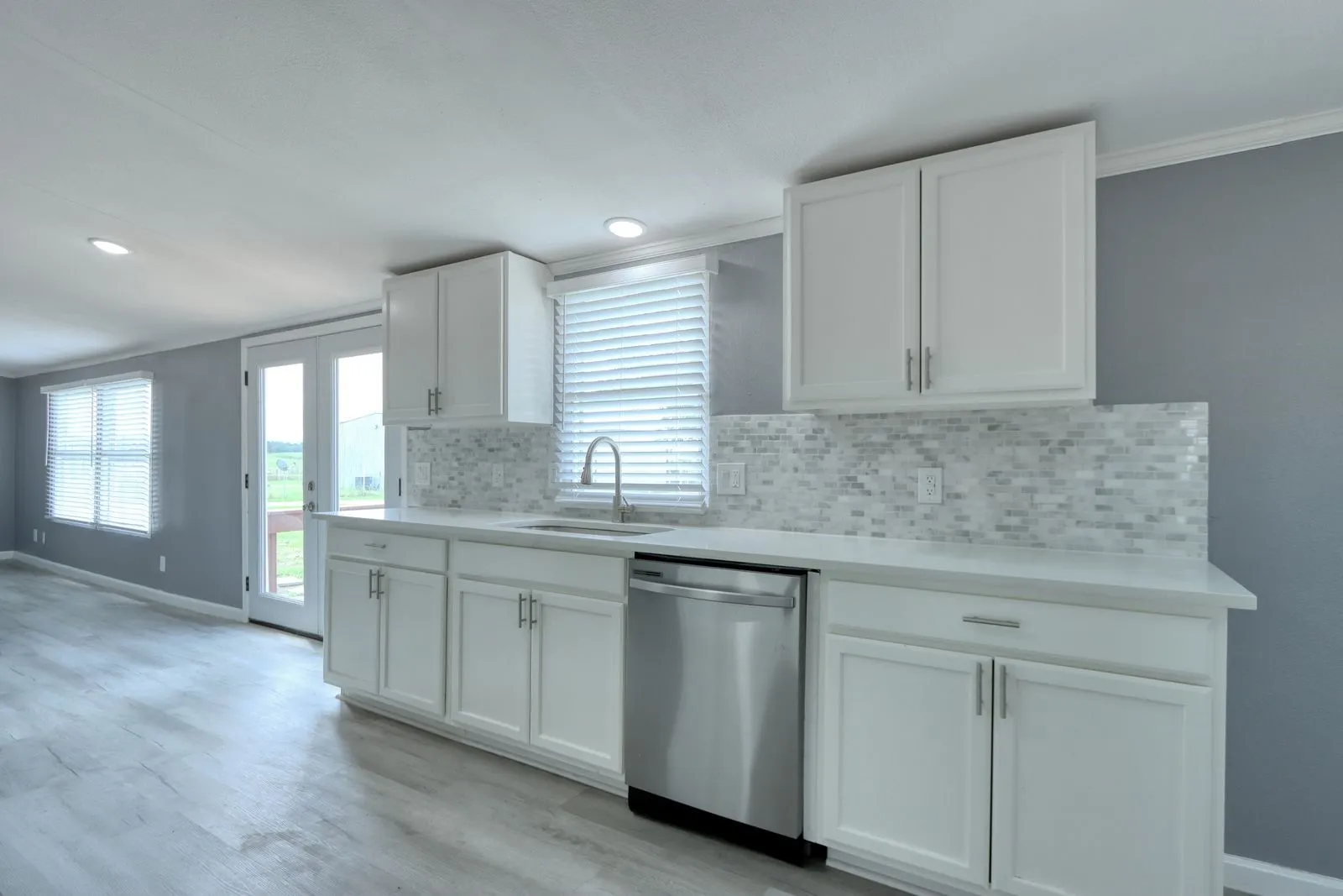 Kitchen featuring white cabinetry, light-toned countertops, and a mosaic tile backsplash
