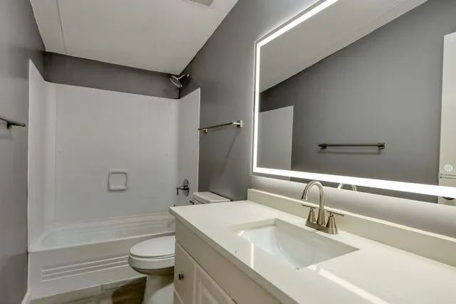 Bathroom vanity featuring a vessel sink, brushed nickel faucet, and an illuminated mirror