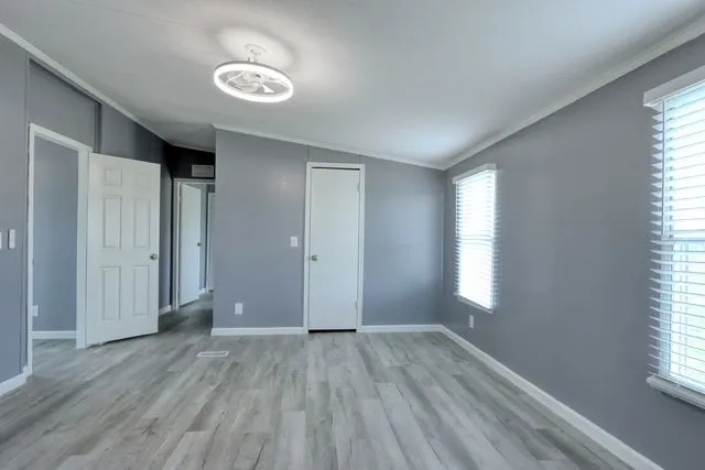 Spacious room featuring light gray walls, wood-finish flooring, and white trim