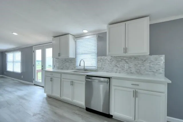 Modern kitchen featuring white shaker cabinetry, light-toned countertops, and a full-height tile backsplash