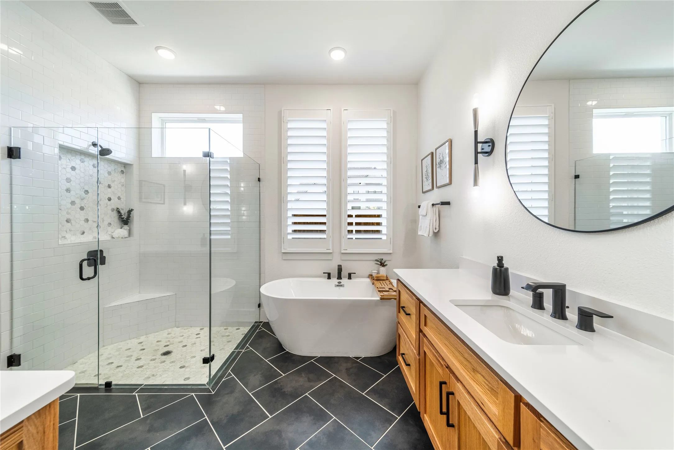 Enjoy a frameless glass shower with bench seat and niche alongside a luxurious freestanding soaking tub.
