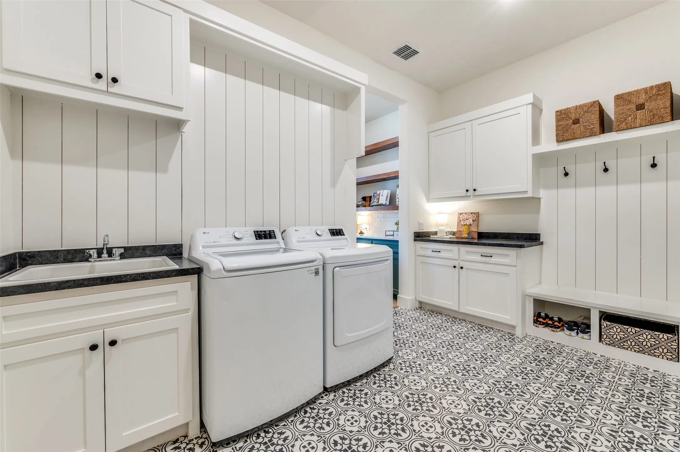 A thoughtfully designed utility room features a folding counter, utility sink, hanging rod, upper cabinetry and a built-in mud bench with hooks and cubbies for great organization.