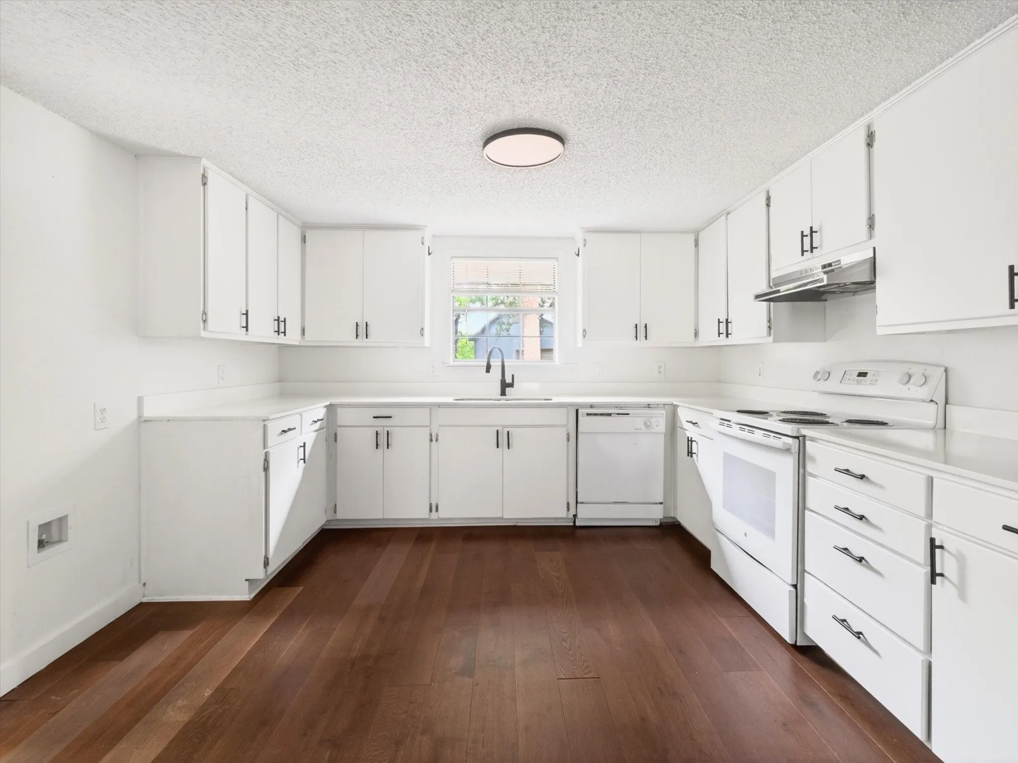 U-shaped kitchen featuring white cabinetry, white countertops, and wood-finish flooring
