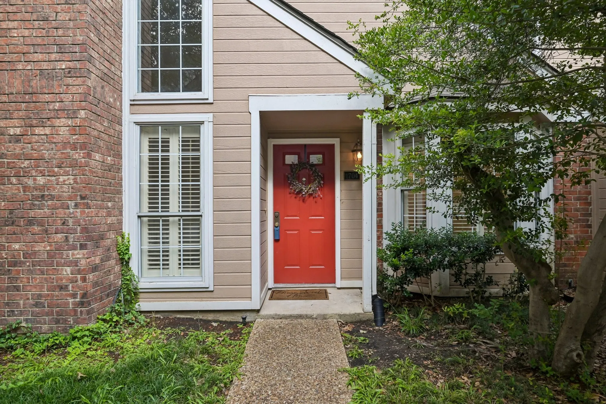 Inviting red front door with an overhead light fixture, set against a façade featuring brick and horizontal siding