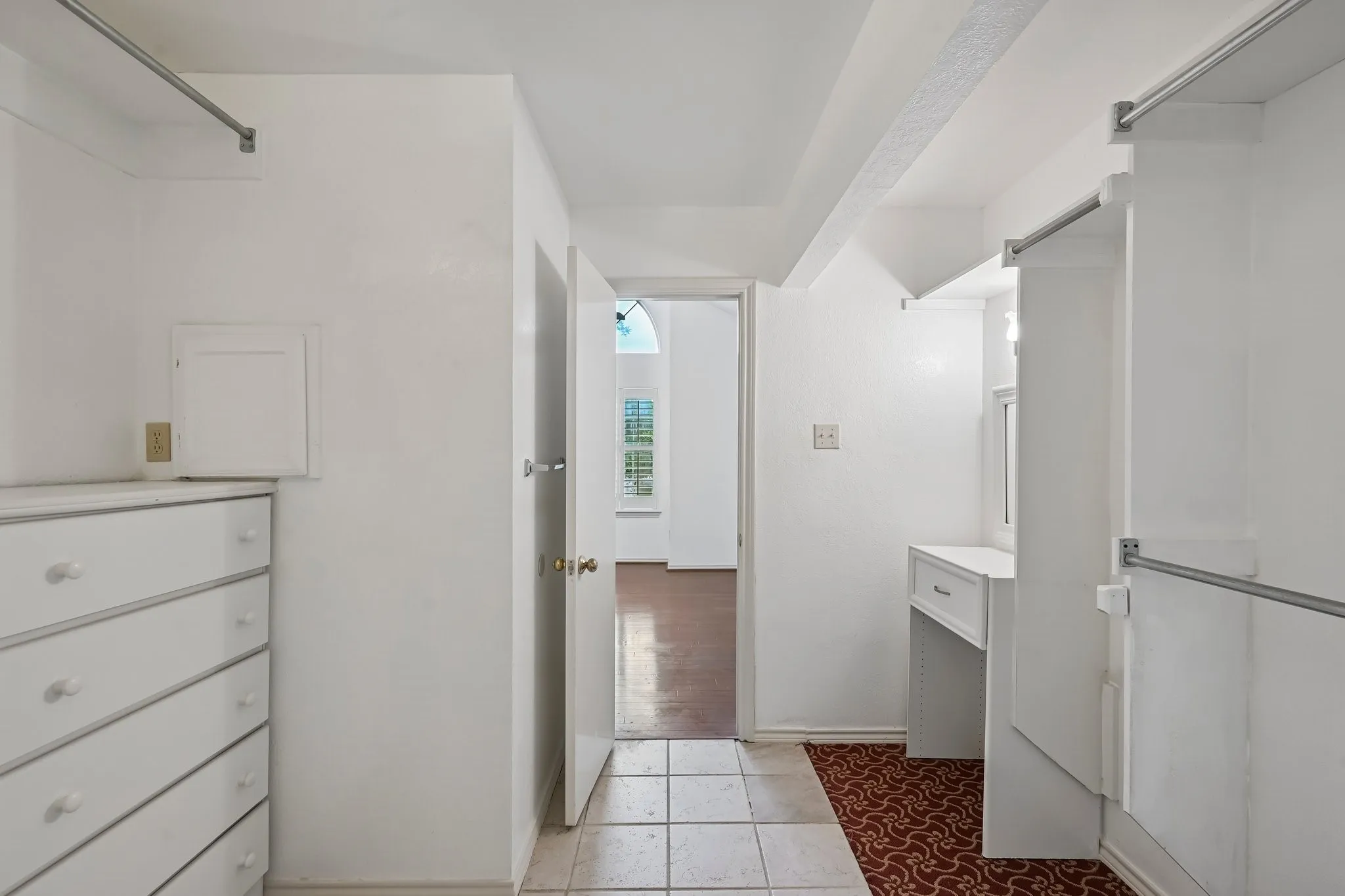 Hallway featuring built-in cabinetry, tile flooring, and integrated clothing rods