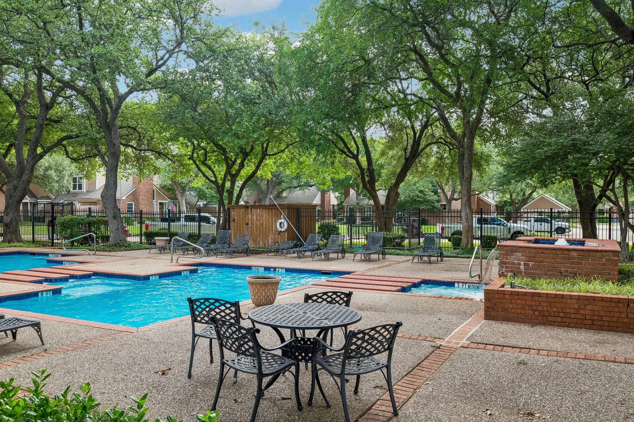 Community swimming pool with surrounding concrete decking and brick accents