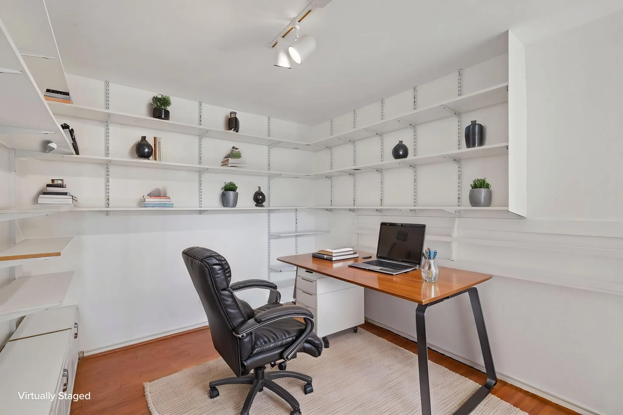 Room featuring extensive wall-mounted shelving, track lighting, and wood-finish flooring