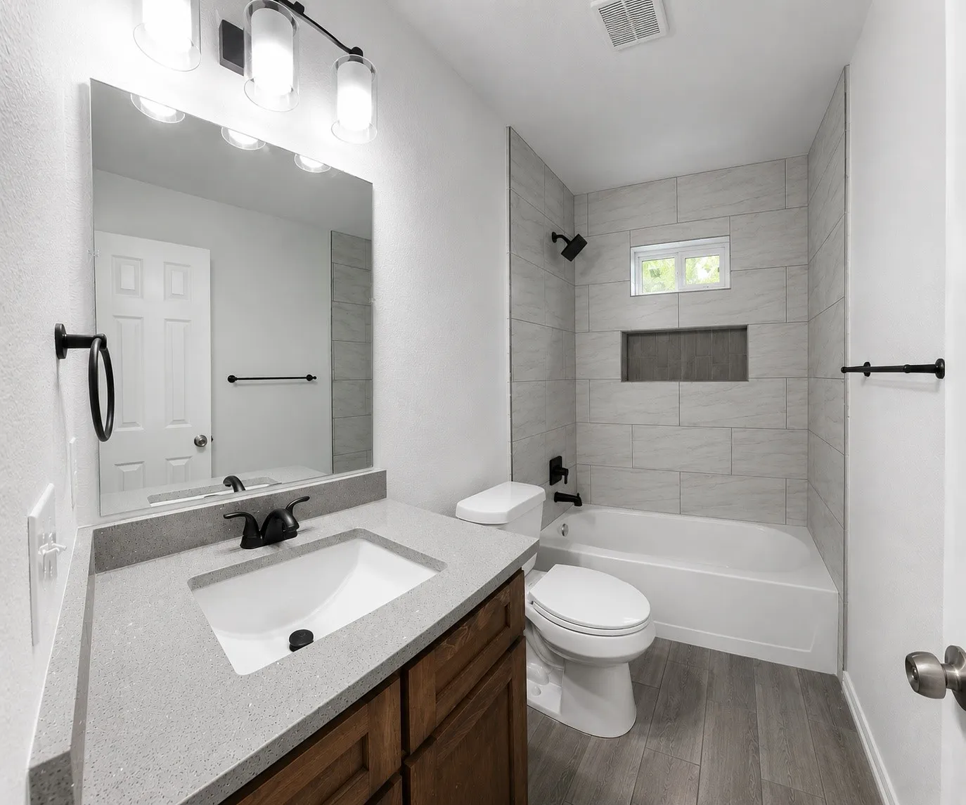 Contemporary bathroom featuring a single vanity with a light-colored countertop, wood-finish cabinetry, and a rectangular undermount sink