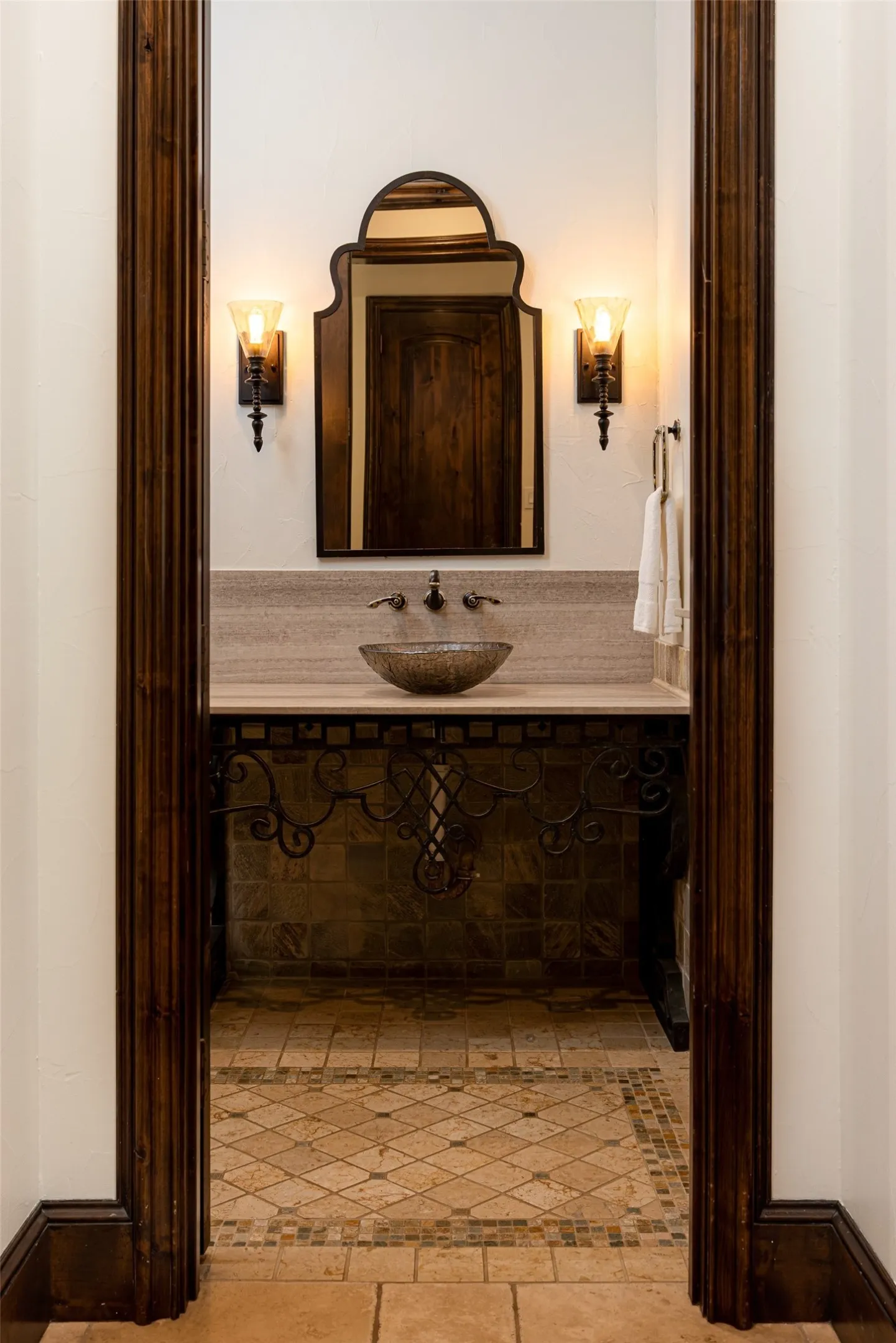 Powder room featuring a decorative vessel sink, wall-mounted faucet, and an ornate framed mirror