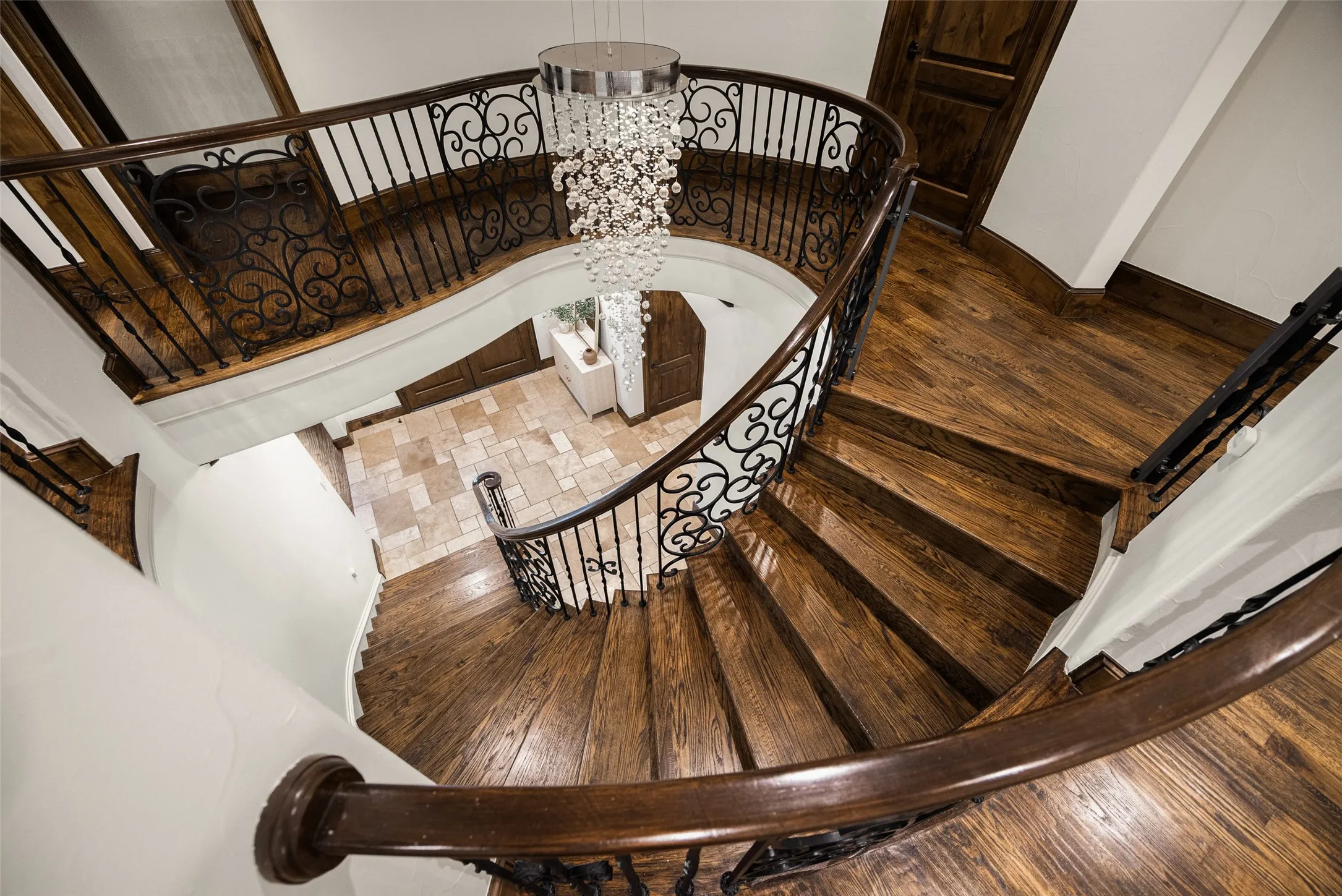 Curved staircase featuring dark wood-finish treads and risers, wrought iron balusters with ornate detailing, and a dark wood-finish handrail