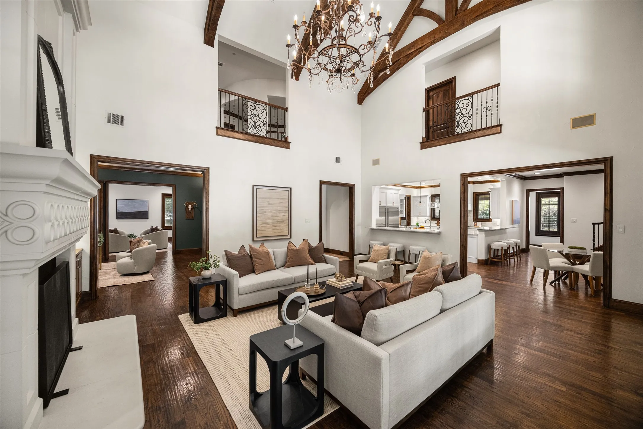 Voluminous living room featuring a vaulted ceiling with exposed wood beams, a decorative chandelier, and rich wood-finish flooring