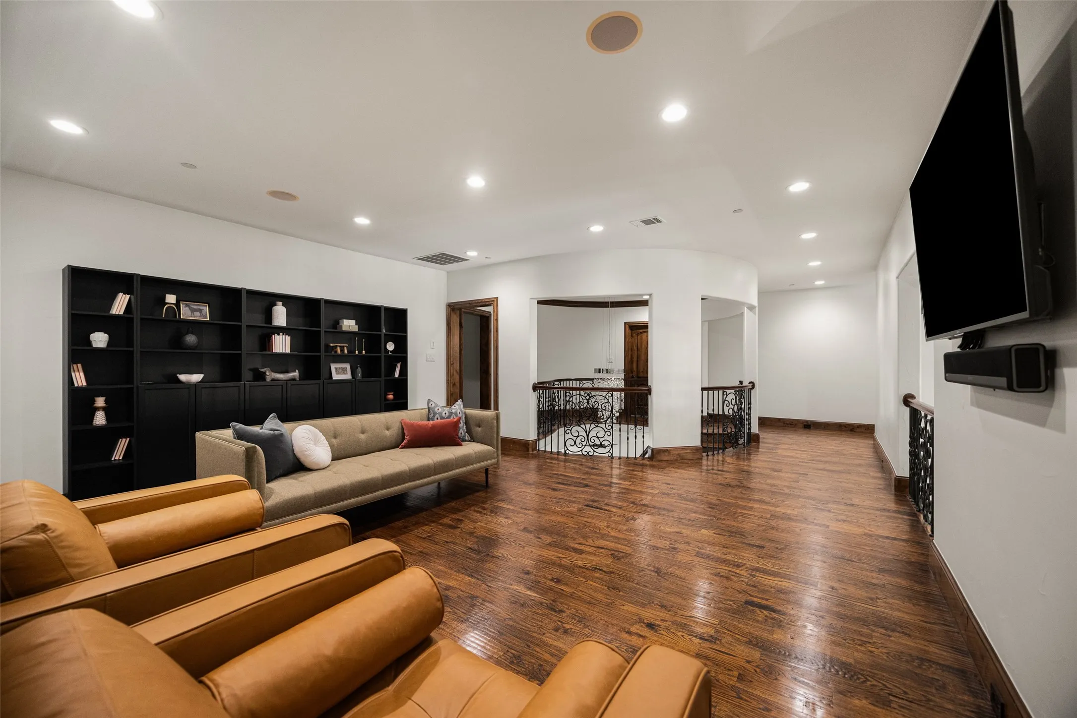 Spacious bonus room featuring wood-finish flooring, recessed lighting, and a built-in shelving unit with lower cabinetry