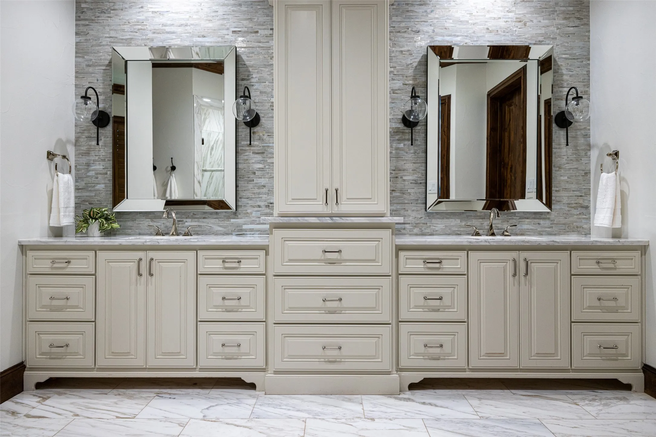 Double vanity with light cabinetry, stone countertops, and a full-height tile backsplash