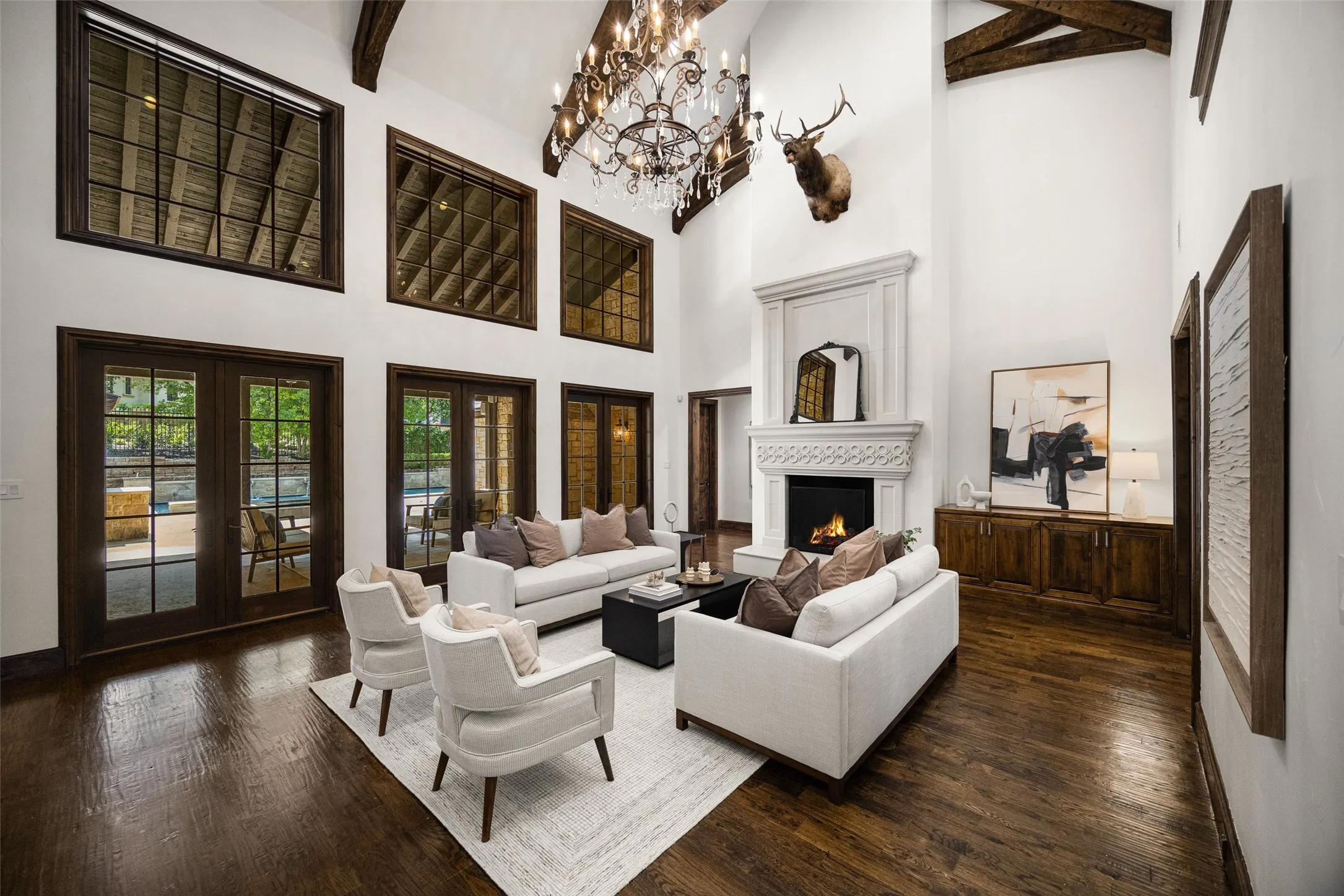 Grand living space featuring a soaring ceiling, dark wood-finish flooring, a stone fireplace, and a large chandelier