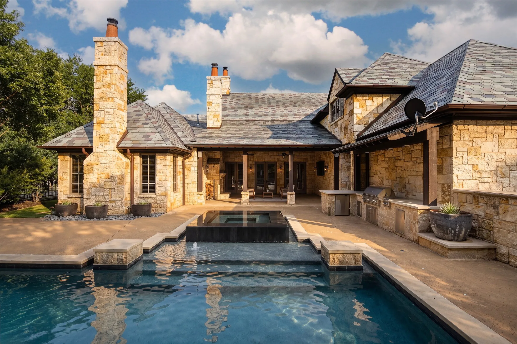 Stone-clad exterior featuring a multi-tiered pool and integrated spa