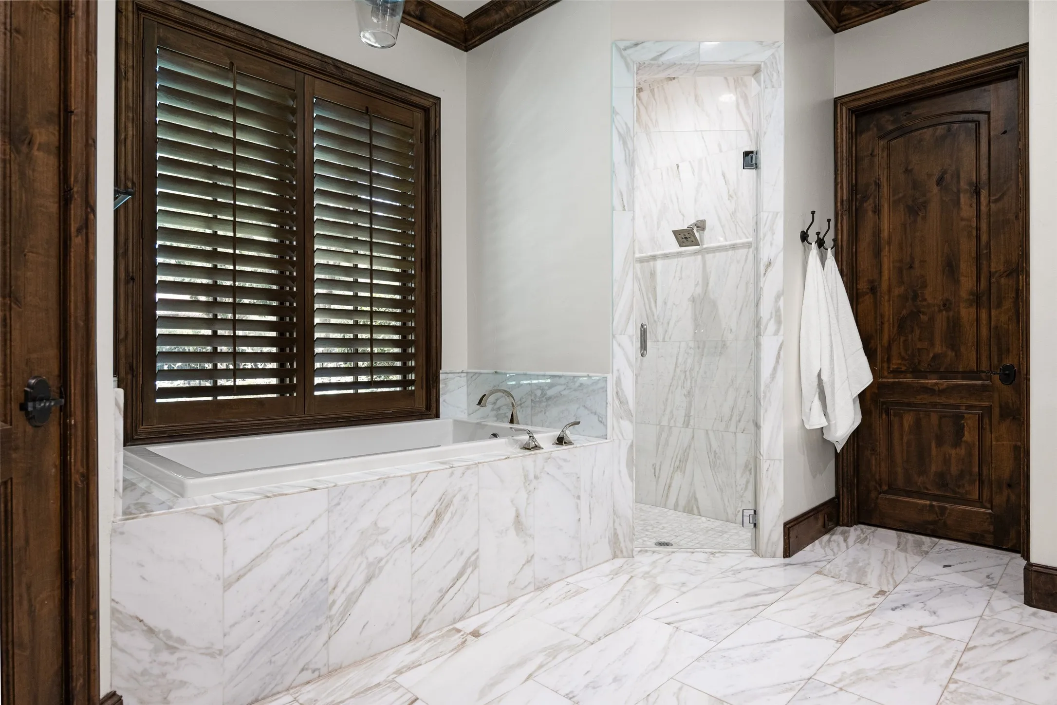 Bathroom featuring a built-in tub with deck-mounted fixtures, a glass-enclosed shower, and wood-finish interior doors