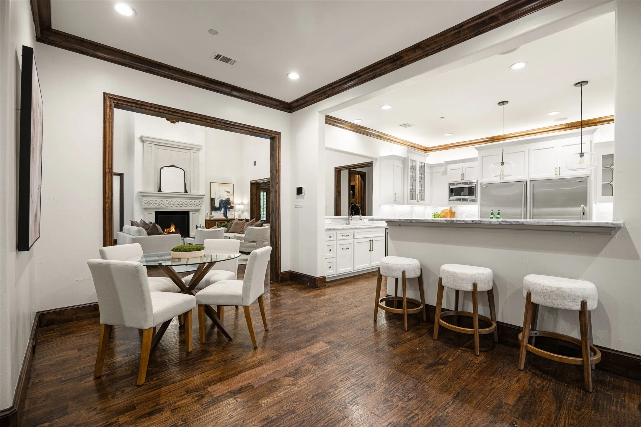 Kitchen featuring white cabinetry, stainless steel appliances, a breakfast bar with stone countertop, and pendant lighting